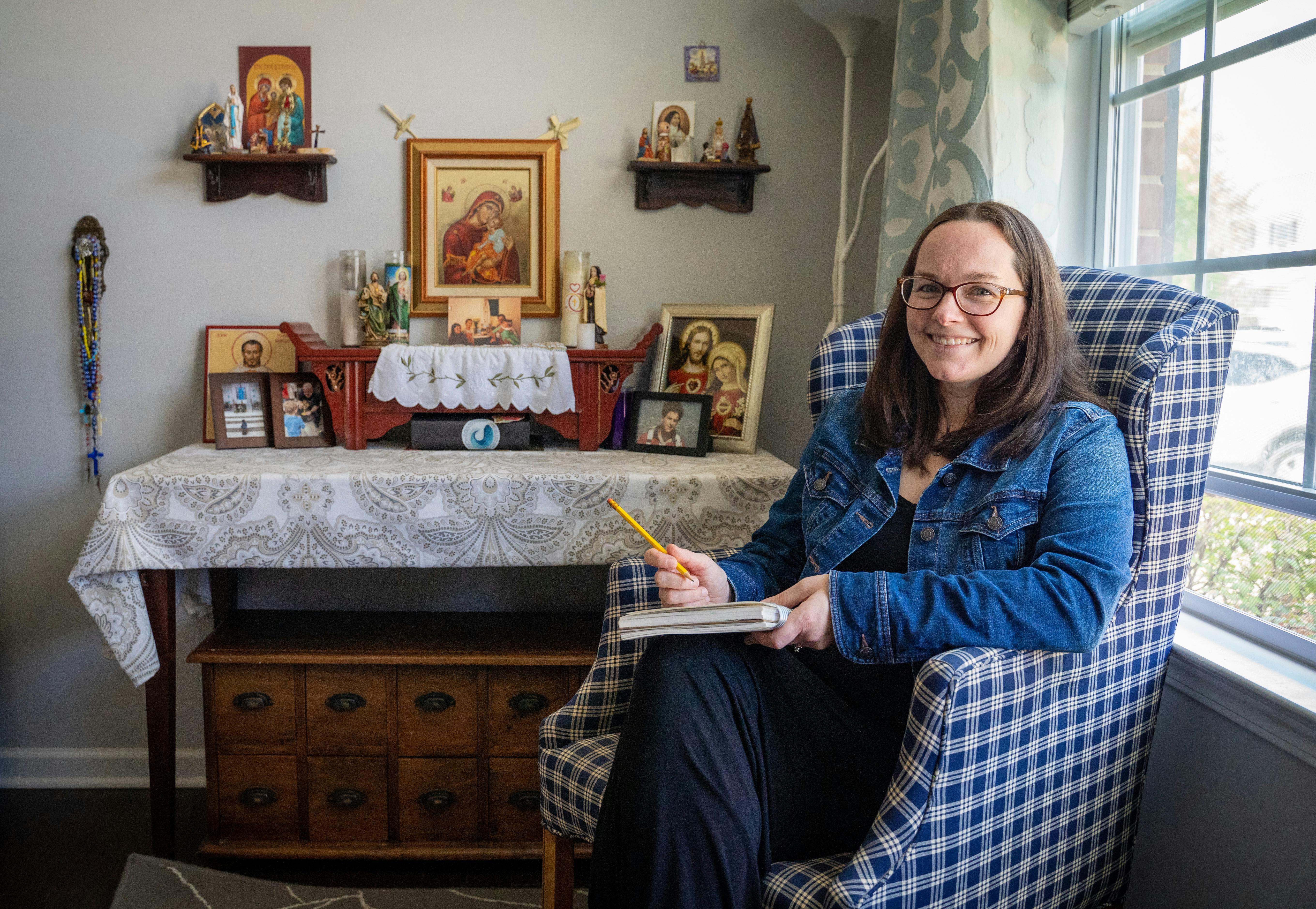 Marie Mattos is pictured with her sketchbook and home altar, which features images of Jesus, Mary and the saints. Mattos, who always loved dabbling in art, majored in studio art at Michigan State and began freelancing a few years ago.