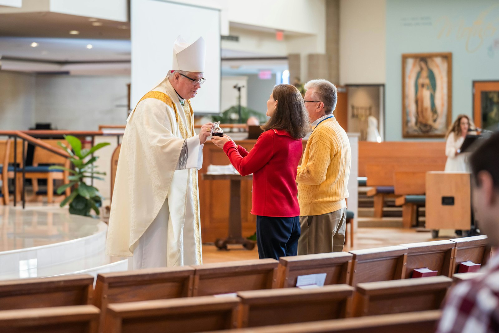 El obispo auxiliar Gerard W. Battersby recibe los regalos de una pareja en el altar durante la Misa para comenzar la conferencia. El obispo Battersby ofreció una bendición para aproximadamente 60 parejas que asistieron a la conferencia.