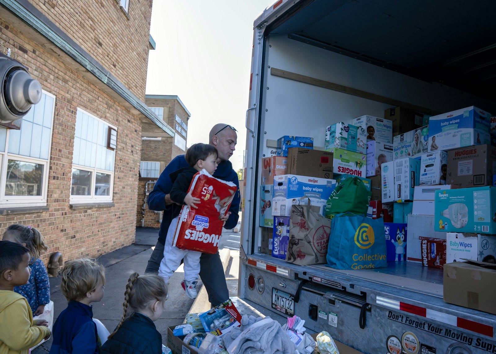 School principal Scott Wisniewski helps a pre-kindergarten student toss a pack of diapers into the back of the truck. The Diocese of Knoxville specifically asked that the Shrine community donate baby and personal hygiene items.