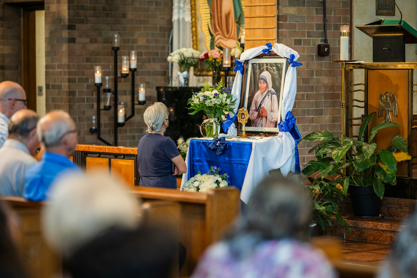 A woman prays in front of a relic of St. Teresa.