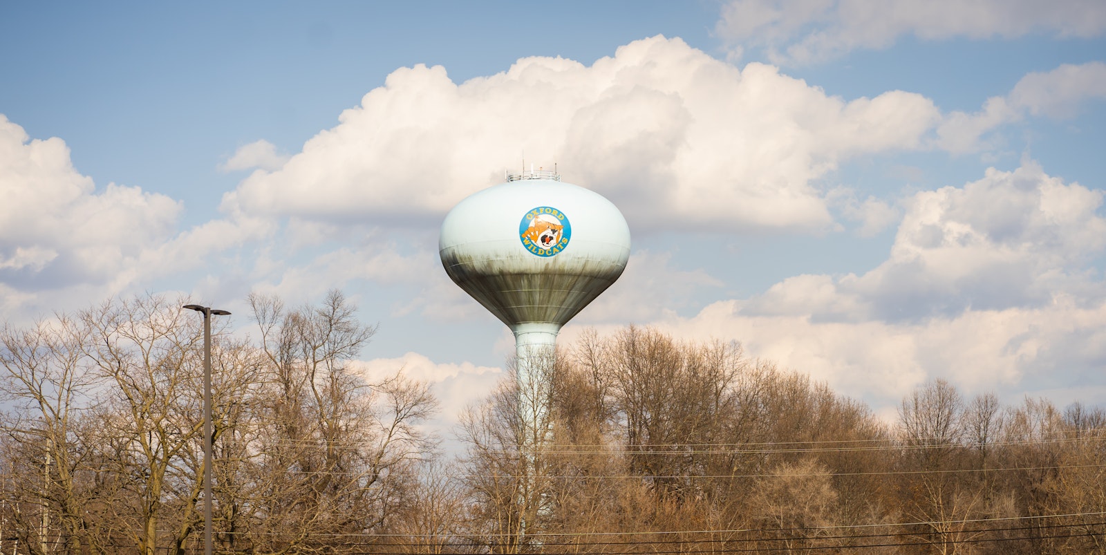 A water tower with the Oxford High School logo is pictured across the street from the high school. The community of 22,000 is at the edge of suburban sprawl, with farm country to the north and suburban neighborhoods to its south.