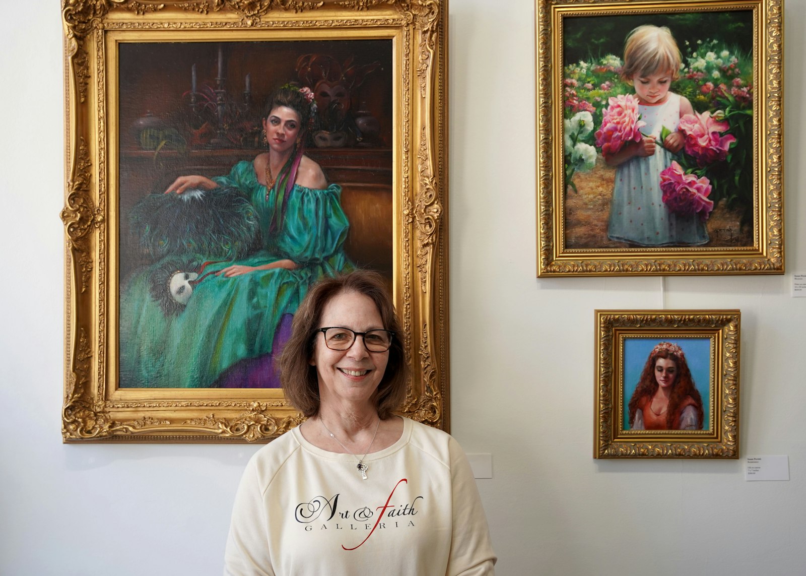 Susan Perrish stands in front of her paintings. While Perrish said that her subject matter is never overtly Catholic, she said that her faith inspires each brush stroke.