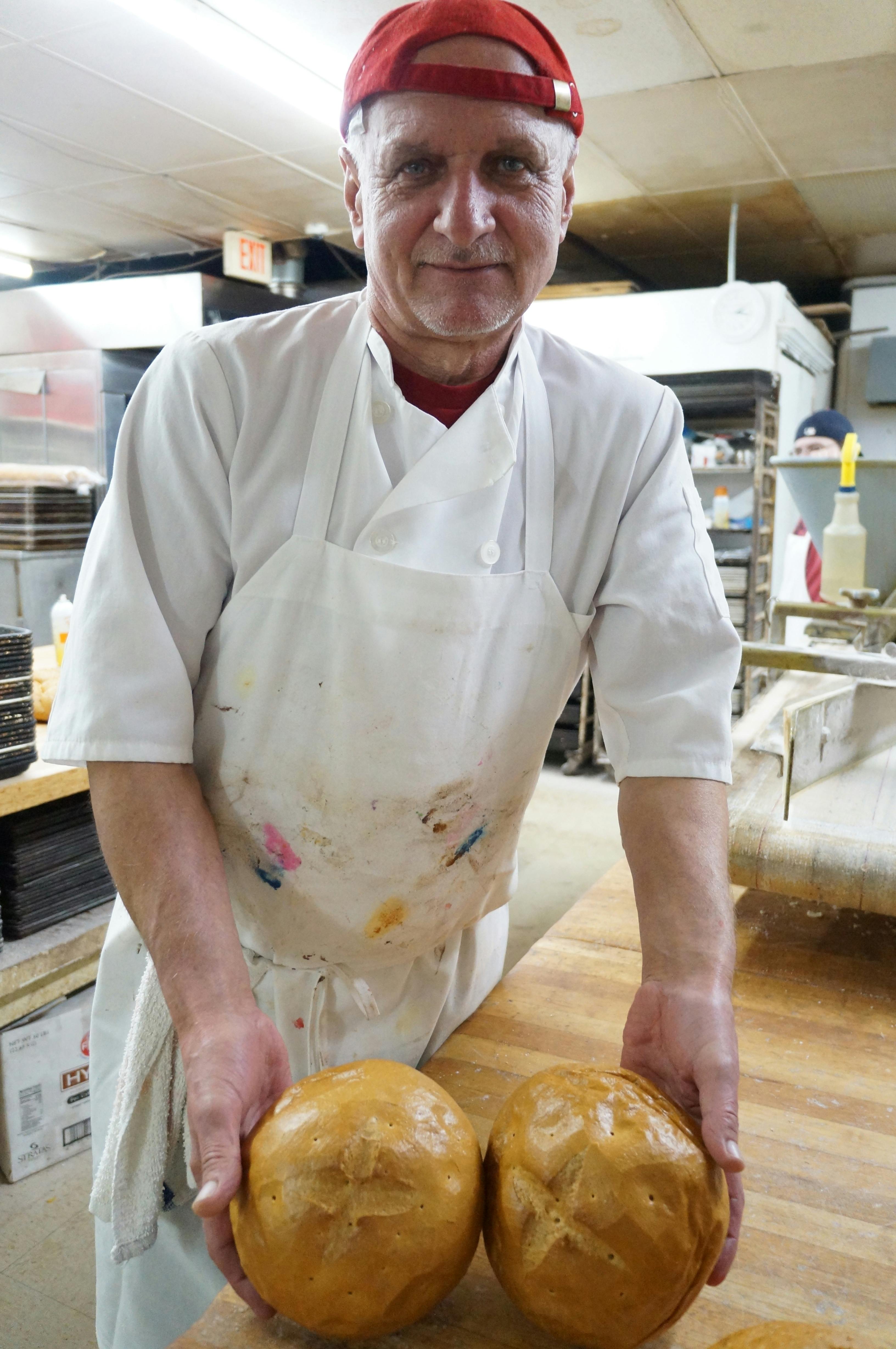 Baker Danny Dimatrivic shows off two bread loaves baked for St. Joseph's feast day. Each ball of dough has a cross carved into the top, the origin of the term "hot cross buns."