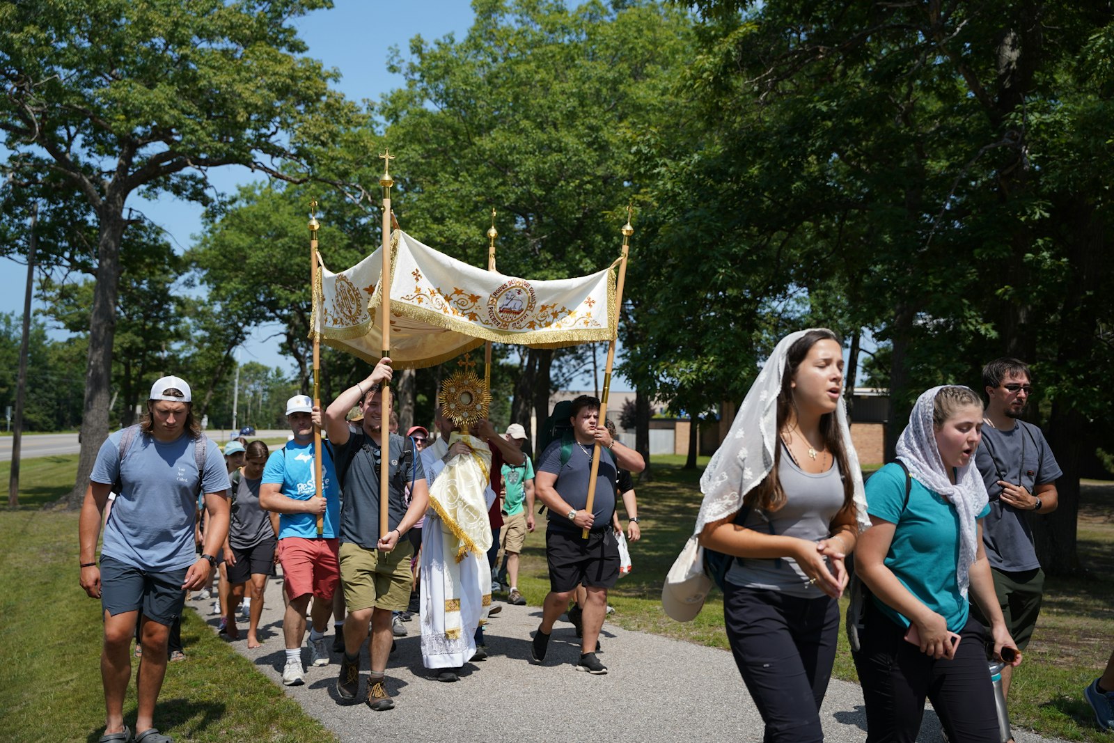 Young adults process with the Eucharist on their way to the National Shrine of the Cross in the Woods in Indian River. The procession crossed through the town of Indian River, which was hosting a fair that day.