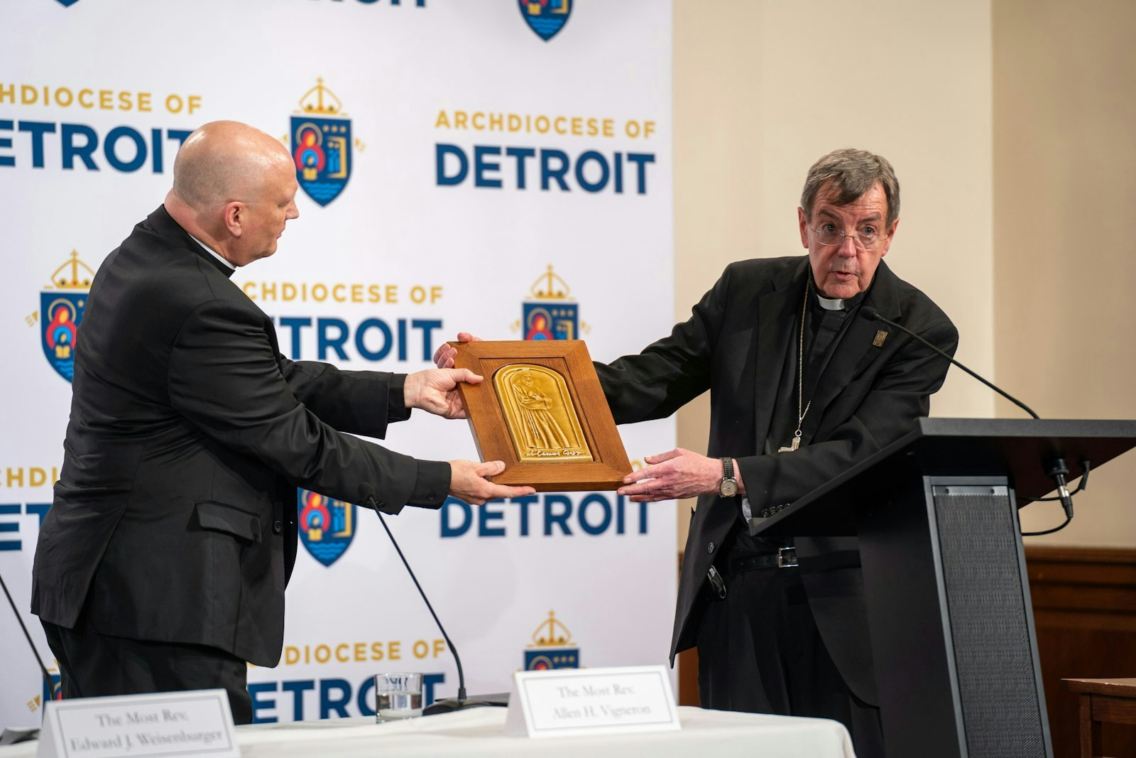 El Arzobispo Allen H. Vigneron (derecha) entrega al Arzobispo electo Edward J. Weisenburger un cuadro de Pewabic con la imagen del Beato Solanus Casey, santo nacido en Detroit. En el Sacred Heart Major Seminary, donde tuvo lugar la conferencia de prensa, se encuentra la segunda colección más grande de cuadros de Pewabic de los Estados Unidos.