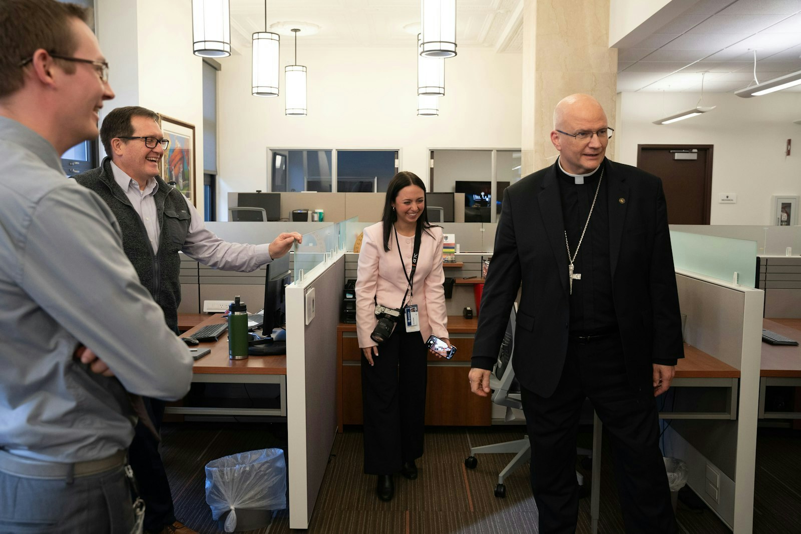 El personal de la Cancillería sonríe mientras el Arzobispo electo Weisenburger se ríe durante una visita al edificio de la Cancillería de la arquidiócesis.