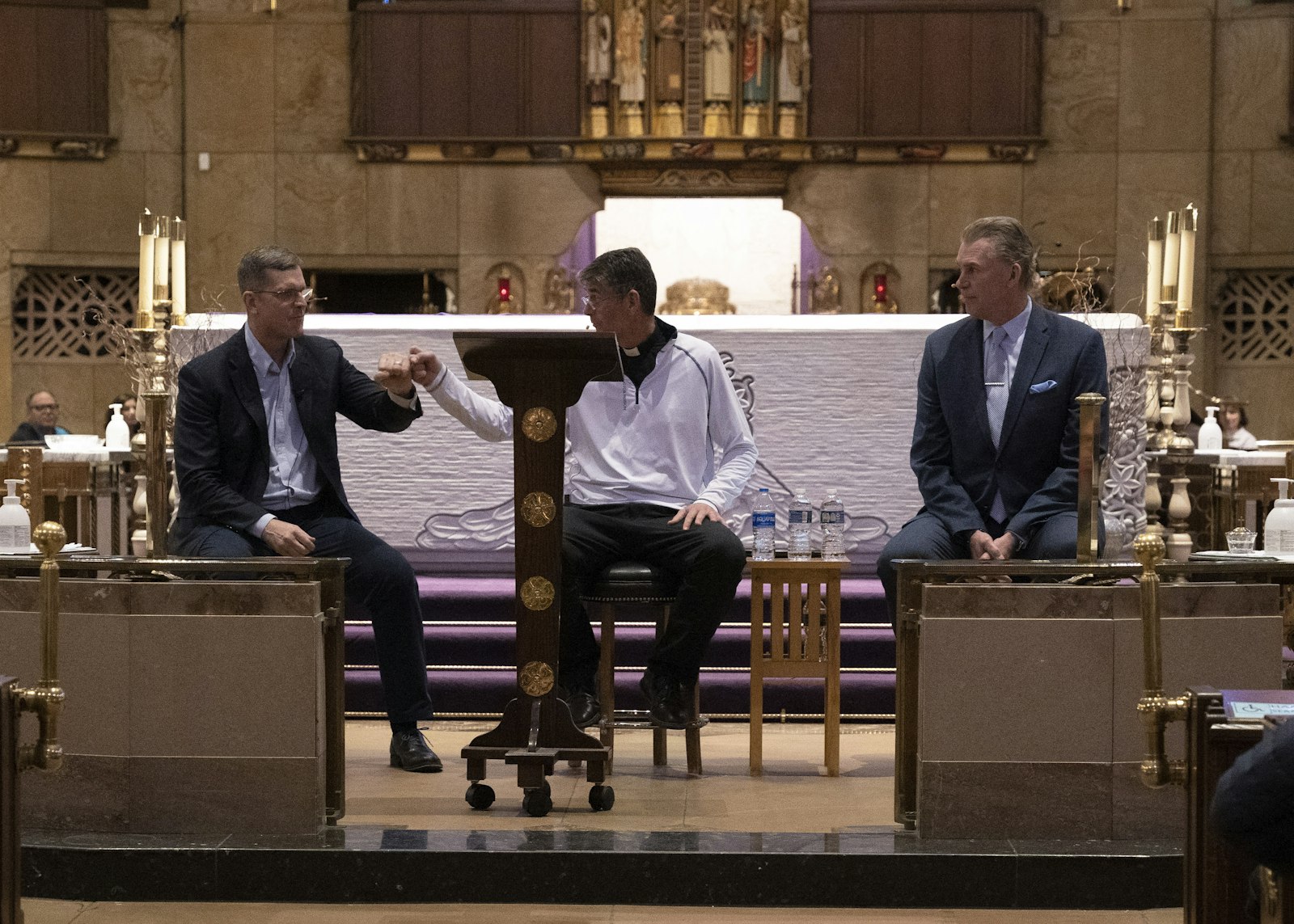 Harbaugh "fist bumps" with Fr. Riccardo as McCormick, right, looks on. The two sports legends, both Catholics, recalled their struggles as young athletes and how their faith and families helped them persevere later in life.