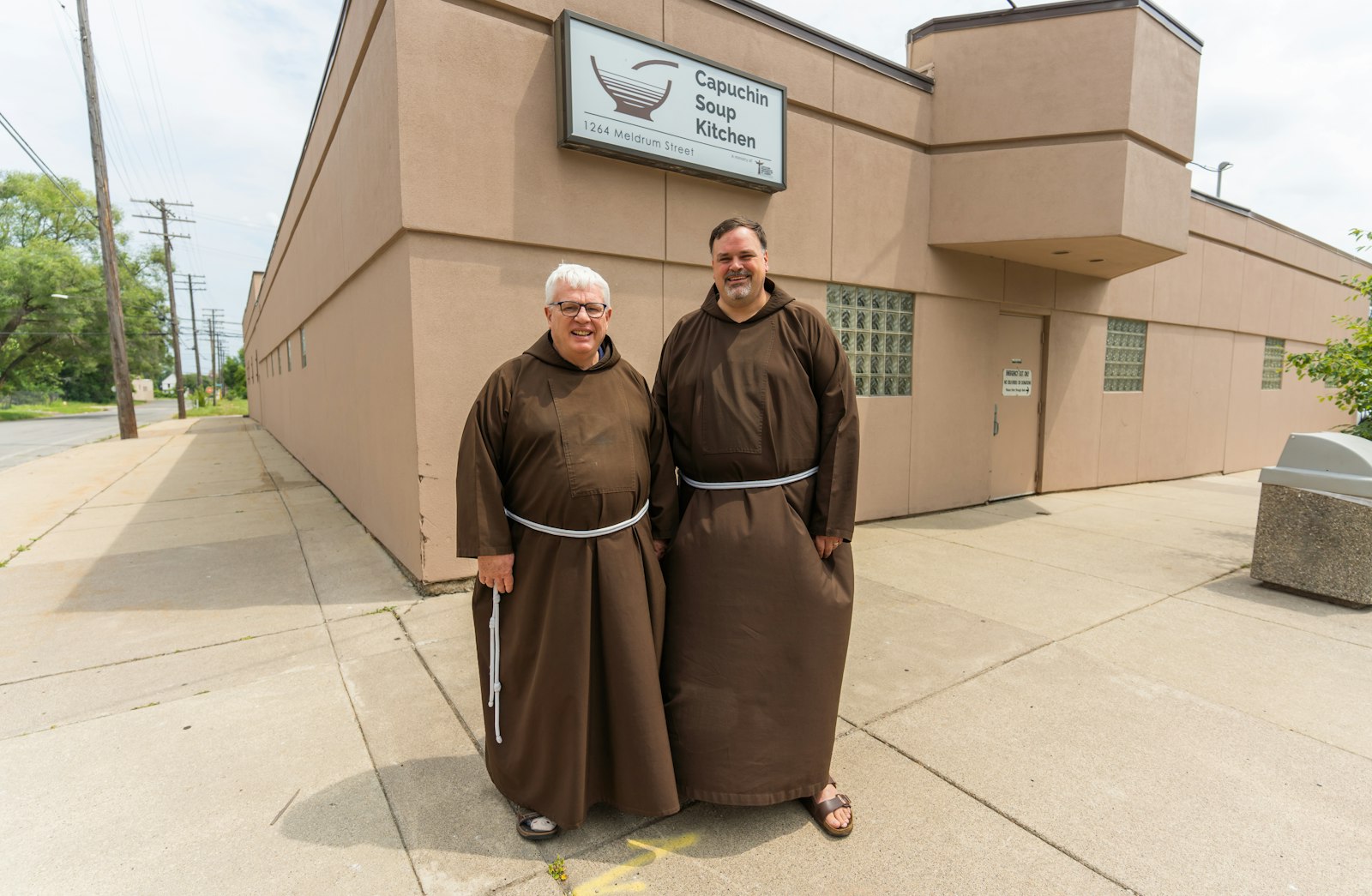 Bro. Gary Wegner, OFM Cap., left, executive director of the Capuchin Soup Kitchen, stands with Bro. Steven Kropp, OFM Cap., director of the Solanus Casey Center, in front of the Capuchin Soup Kitchen in August 2021. (Valaurian Waller | Detroit Catholic)