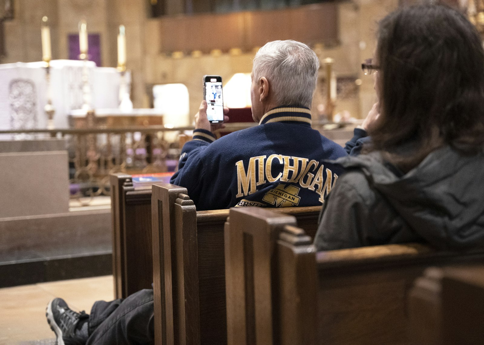 A University of Michigan fan films the speaker series event on his smartphone. The "Live at the Basilica" speaker event drew a full congregation at the National Shrine of the Little Flower Basilica.