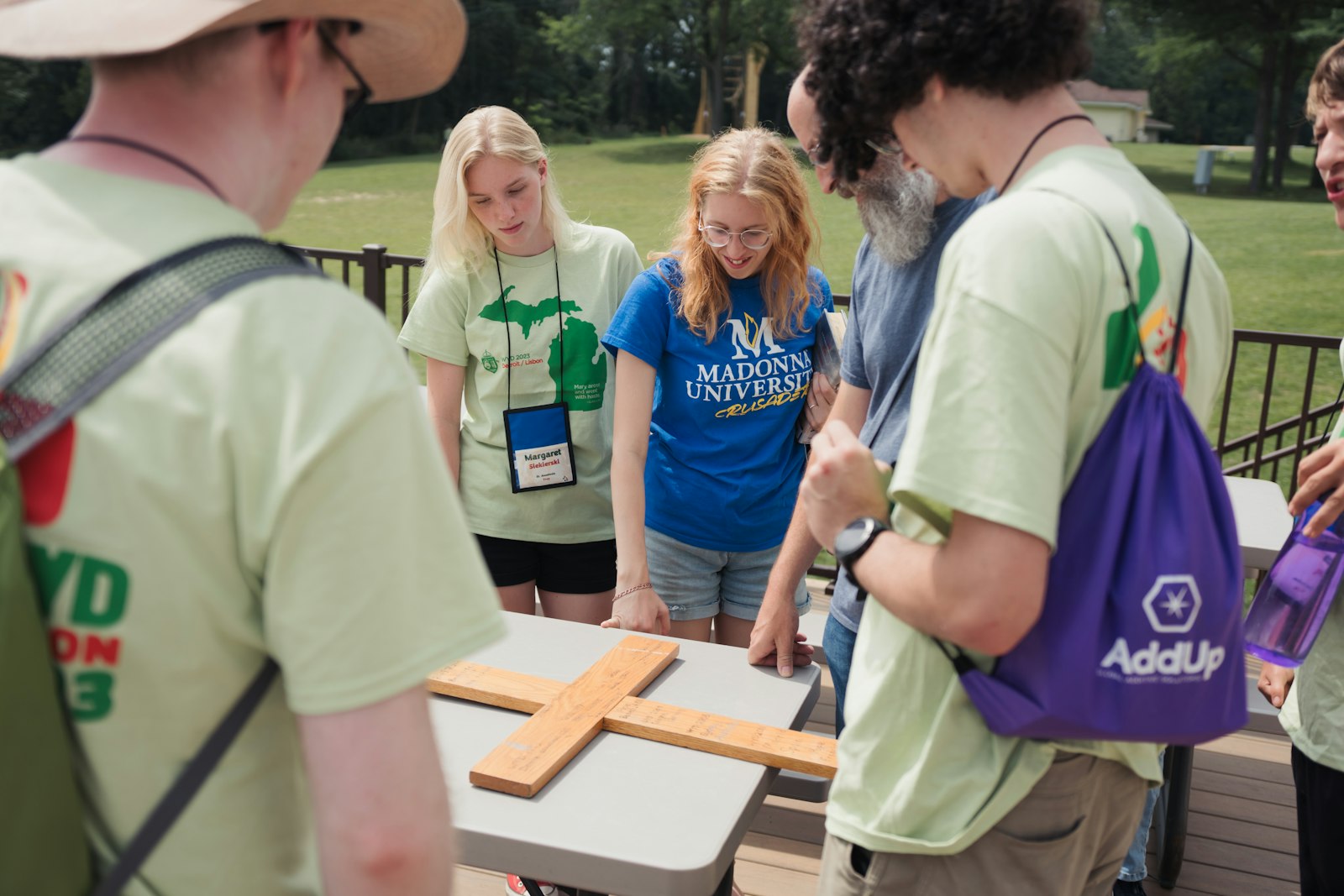 Young people carry a wooden cross signed with the locations and dates of each prior World Youth Day during the World Youth Day "Home" event at Our Lady of the Fields Camp in Brighton in August 2023.