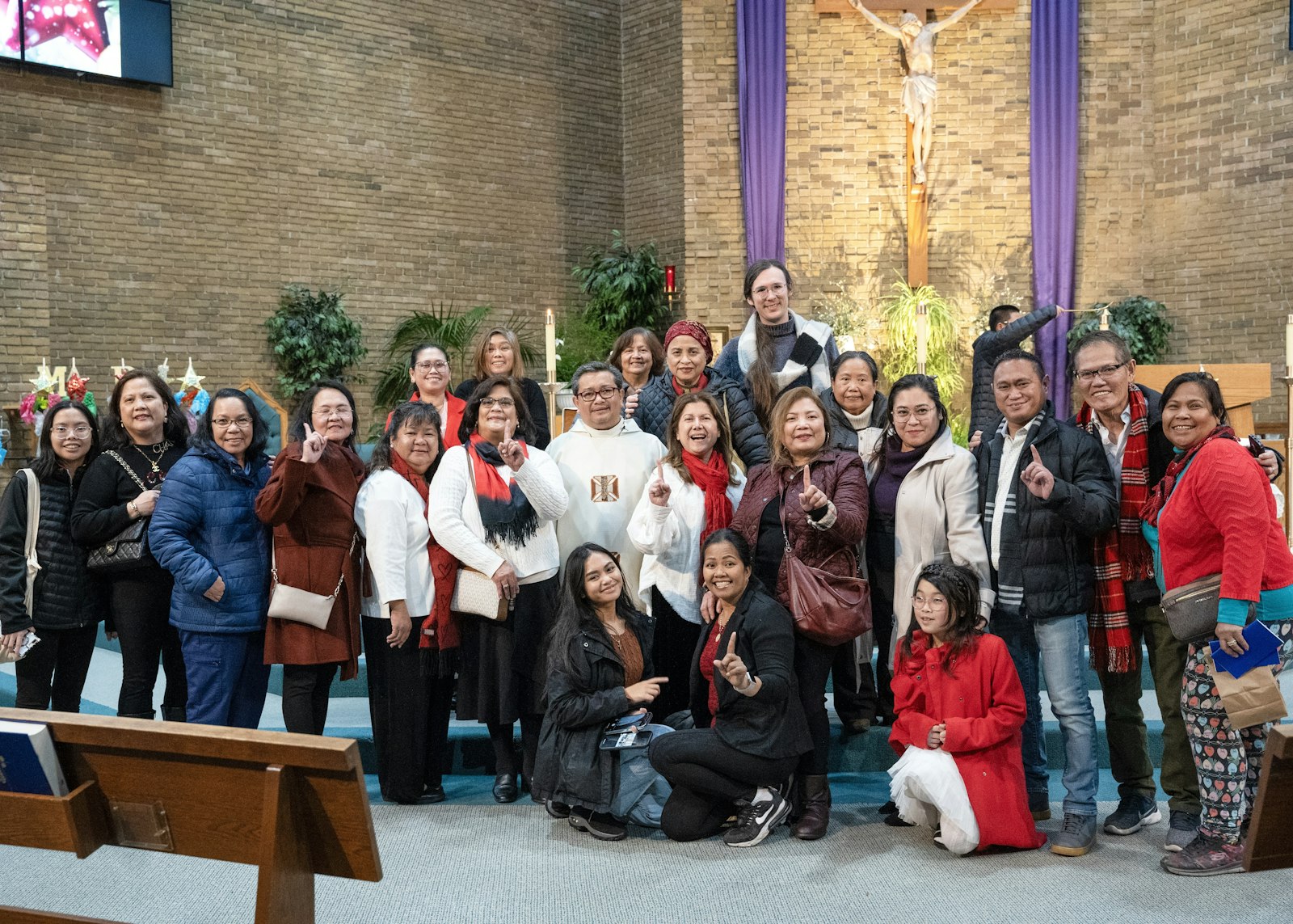 Members of the Filipino community at St. Mary, Cause of Our Joy Parish in Westland hold up the number one during the first night of Simbang Gabi, a nine-day celebration of Masses in anticipation of Christmas, on Dec. 15 at St. Mary, Cause of Our Joy Parish in Westland.