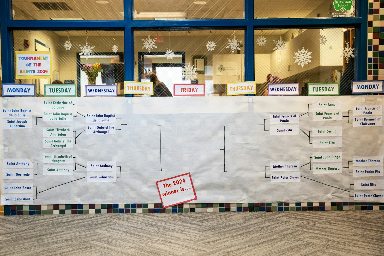 The 2024 bracket is on display at the schoo entrance, and includes a variety of saints.