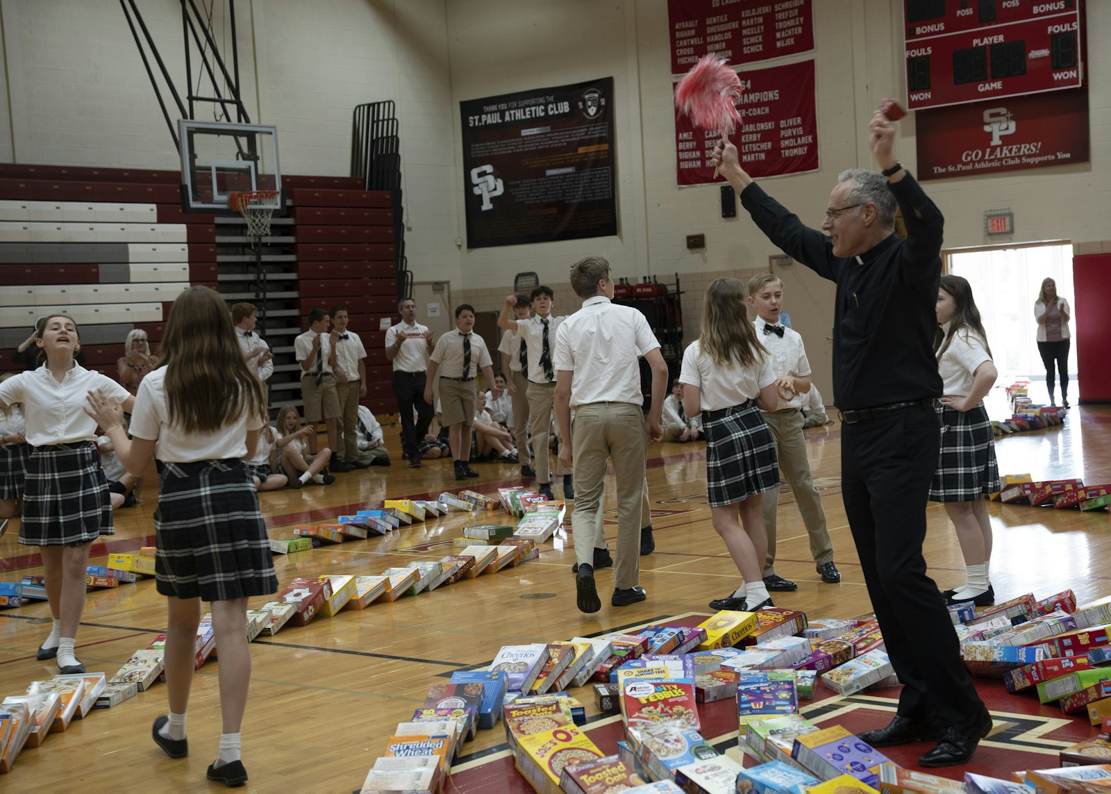 Fr. Jim Bilot waves pom-poms from the center of the domino chain as students cheer the effort on.