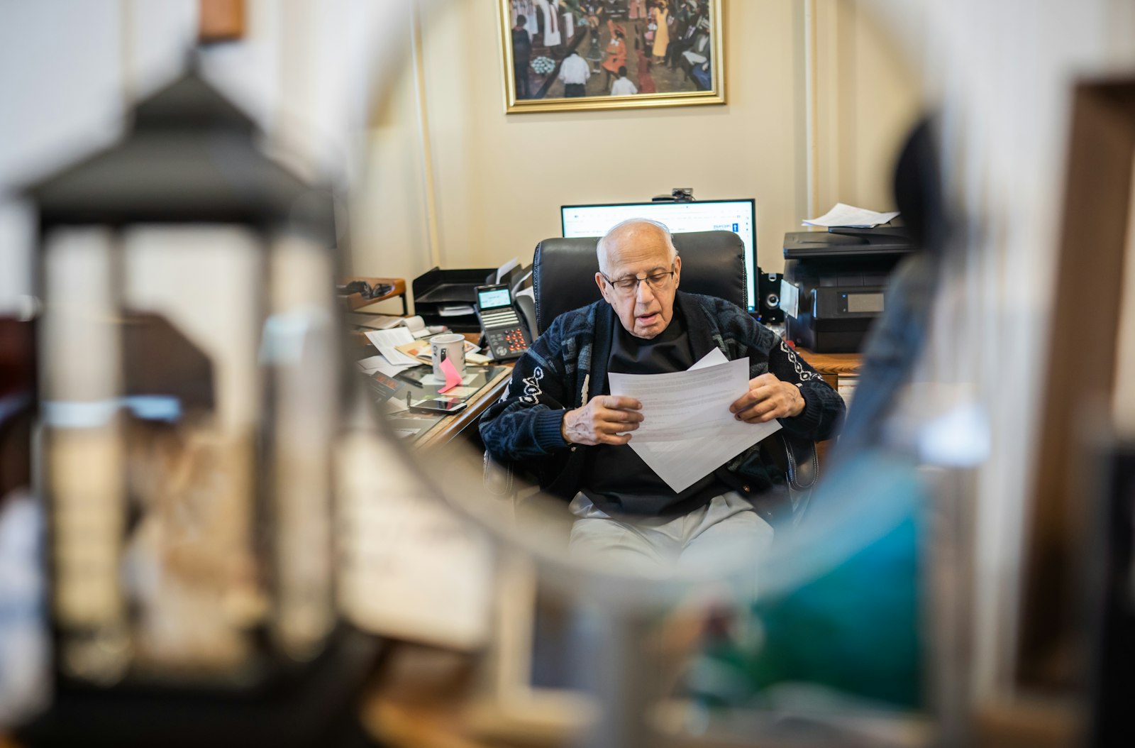 Fr. Thomas goes over paperwork in his office at Sacred Heart Parish in Detroit, where he began serving as pastor in 1968. At 92, he relies more these days on his parish staff, but says he's never considered retiring.