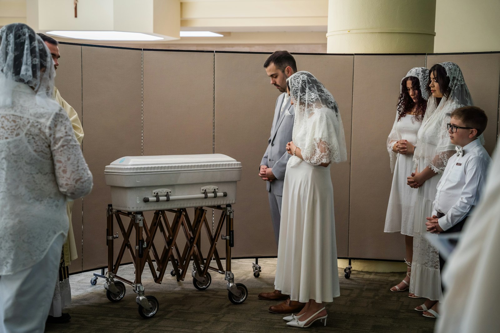 Austin and Nicole LeBlanc pray over the casket of their twin daughters, Maria Teresa and Rachel Clare, before their funeral Mass on May 31 at the Church of the Divine Child in Dearborn. (Valaurian Waller | Detroit Catholic)