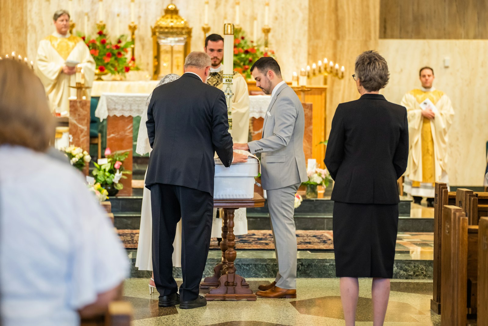 Fr. David Pellican presides over the funeral Mass of Maria Teresa and Rachel Clare LeBlanc on May 31 at the Church of the Divine Child in Dearborn as their parents, Austin and Nicole LeBlanc, place their hands over the tiny casket. (Valaurian Waller | Detroit Catholic)