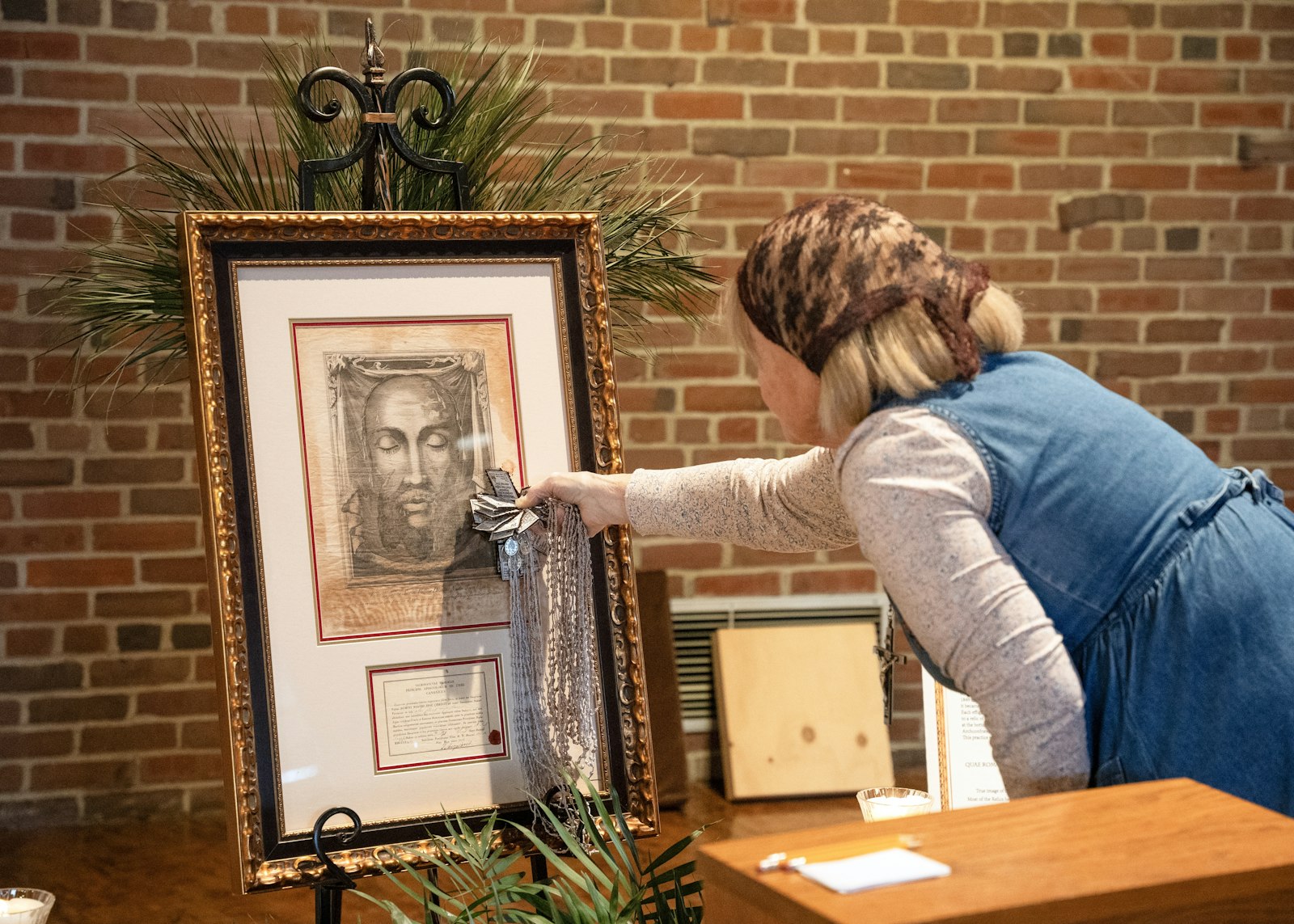 A woman touches rosaries to the Holy Face relic at St. John Fisher Chapel University Parish in Auburn Hills, which is hosting the relic during Holy Week.