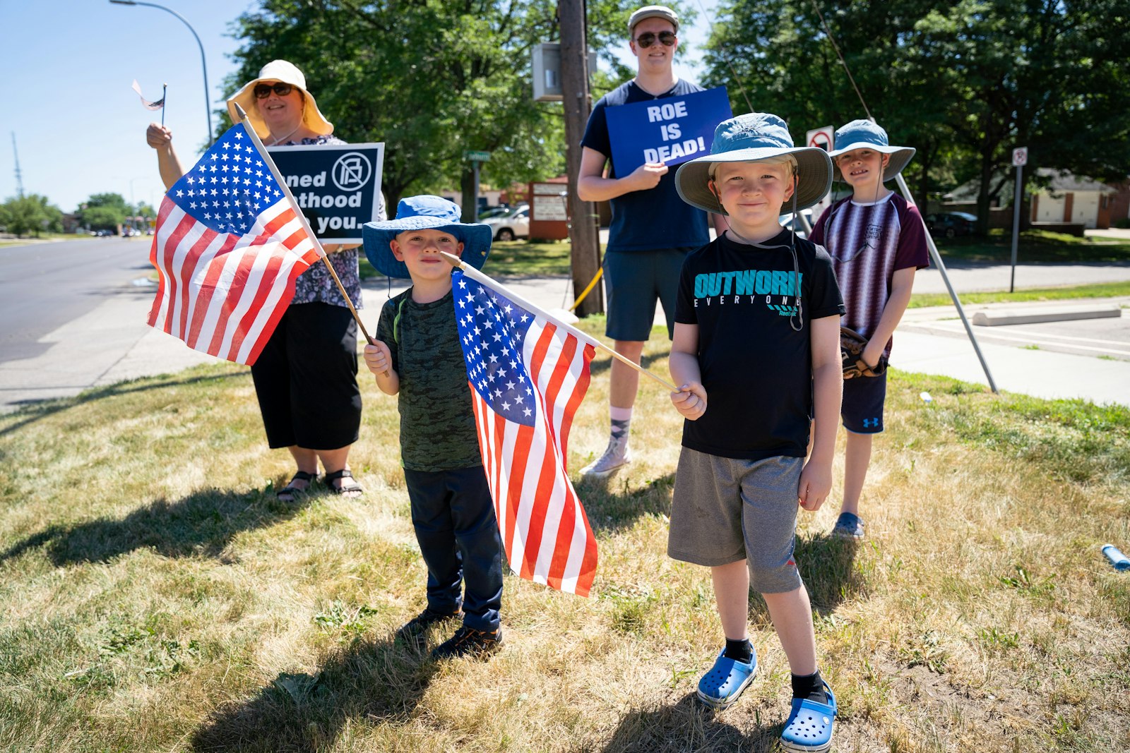 La familia Wilson sostiene pancartas y banderas estadounidenses a lo largo de Farmington Road, en Livonia, el 24 de junio, horas después de la decisión del Tribunal Supremo de anular el caso Roe v. Wade.