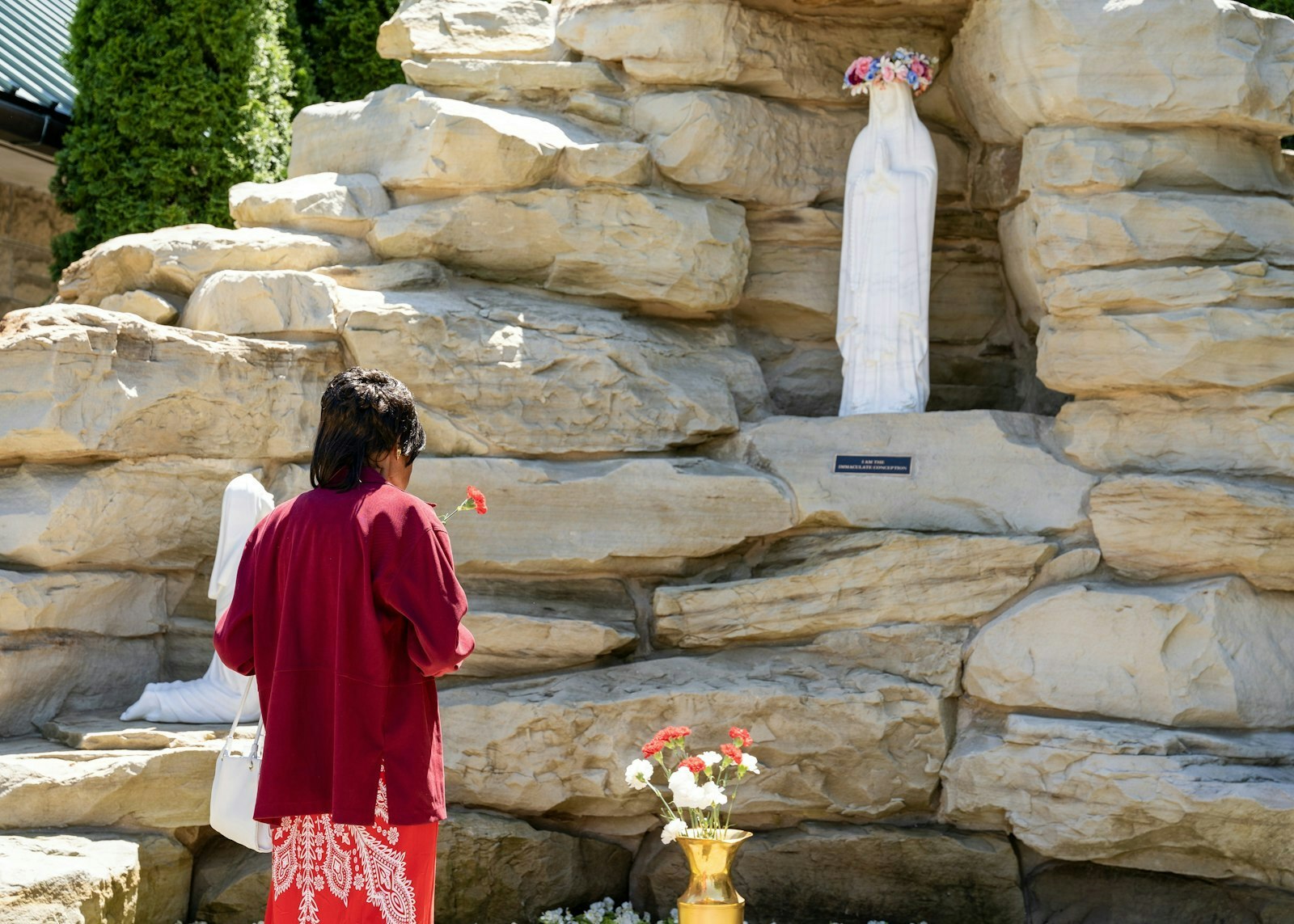 En el Día de las Madres, una mujer reza frente a la recién inaugurada gruta dedicada a Nuestra Señora de Lourdes que se encuentra afuera de la Cathedral of the Most Blessed Sacrament.