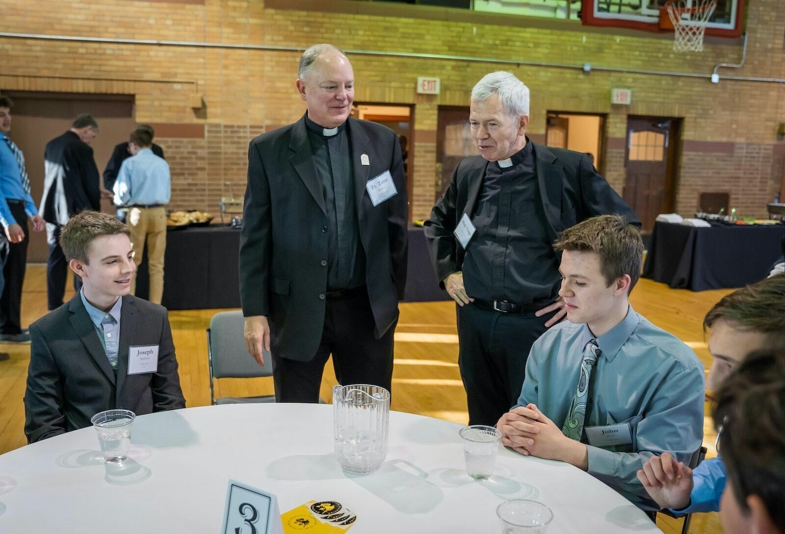 Msgr. Trapp, second right, and Fr. Tony Richter talk with young men attending a vocational discernment dinner with Detroit Archbishop Allen H. Vigneron at Sacred Heart Major Seminary on March 28, 2023. Msgr. Trapp served as a graduate spiritual director for seminarians and associate professor of theology, liturgy and the sacraments at the seminary for more than 35 years. (Valaurian Waller | Detroit Catholic)