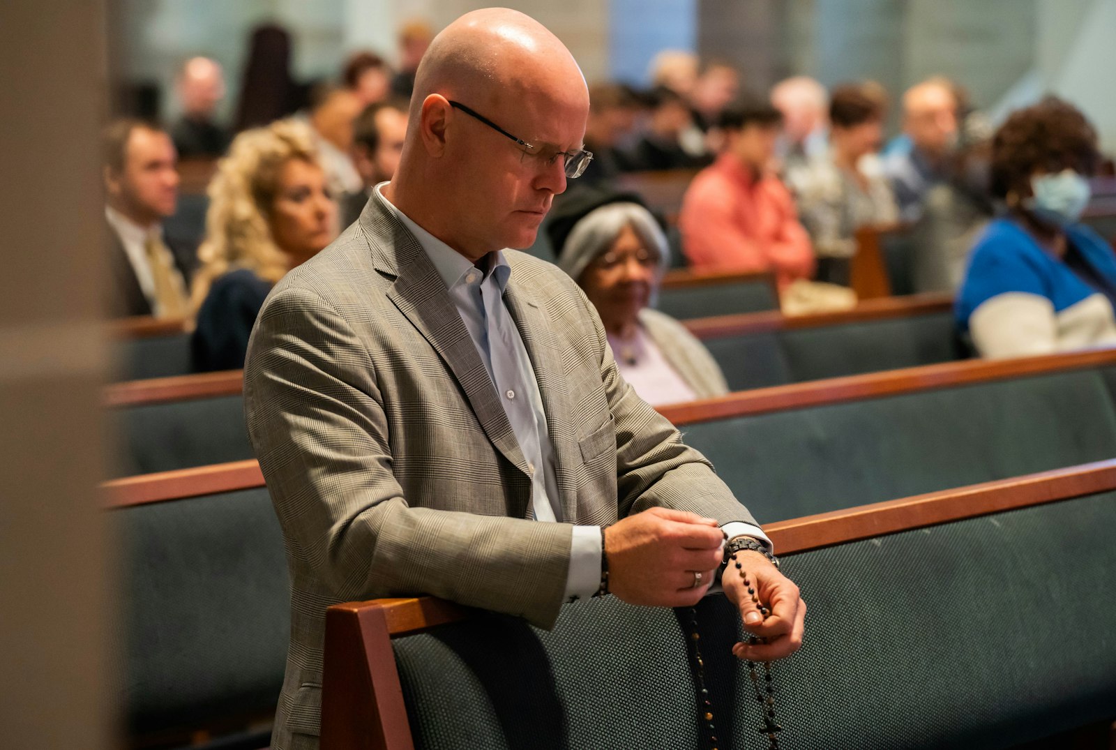 A man clutches his rosary as he prays during the Respect Life Mass. Archbishop Vigneron said three types of action are needed to defeat Proposal 3: the faithful must pray, vote and give.