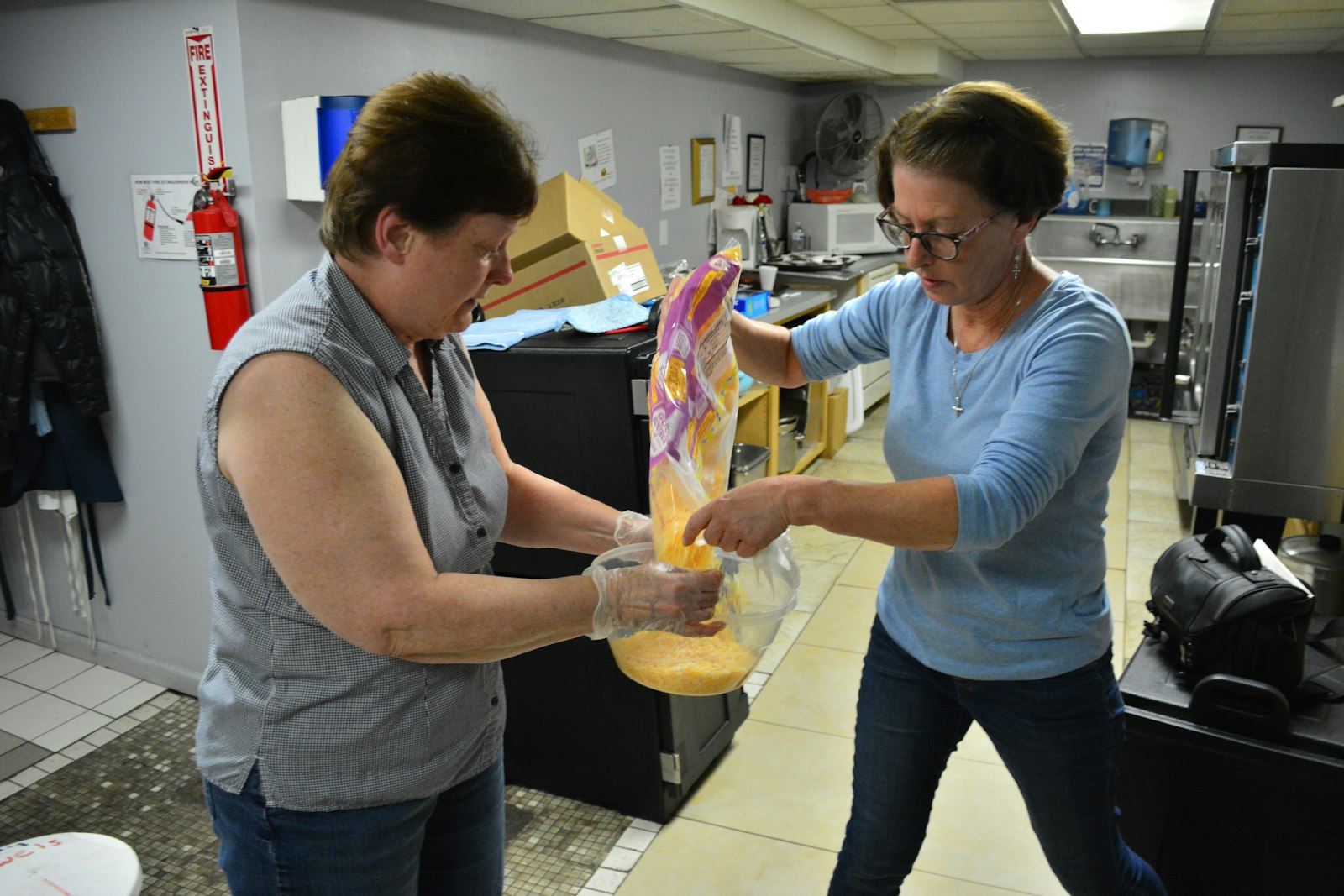 Val Thompson, Christian service coordinator for St. Mary Parish in Milford, right, helps Peggy Cottington, a volunteer from the parish, refill the cheese bowl during a Mexican-themed dinner at Hope Warming Center in Pontiac on Dec. 4, 2017. (Michael Stechschulte | Detroit Catholic file photo)