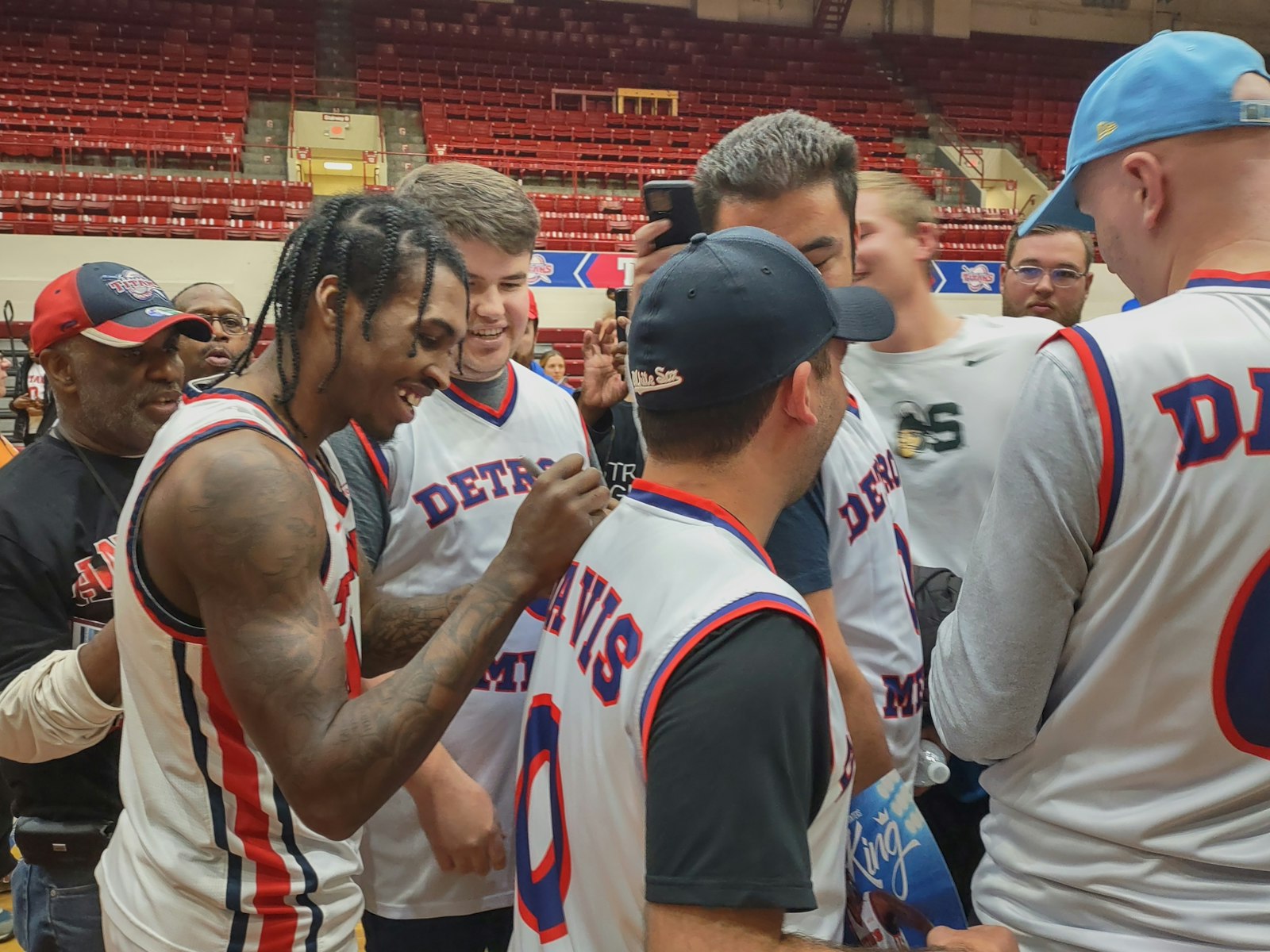 Following a 45-minute post-game ceremony in his honor, Antoine Davis signs autographs for a group of Detroit Mercy fans bearing replicas of his Titan basketball jersey. (Photo by Wright Wilson | Special to Detroit Catholic)