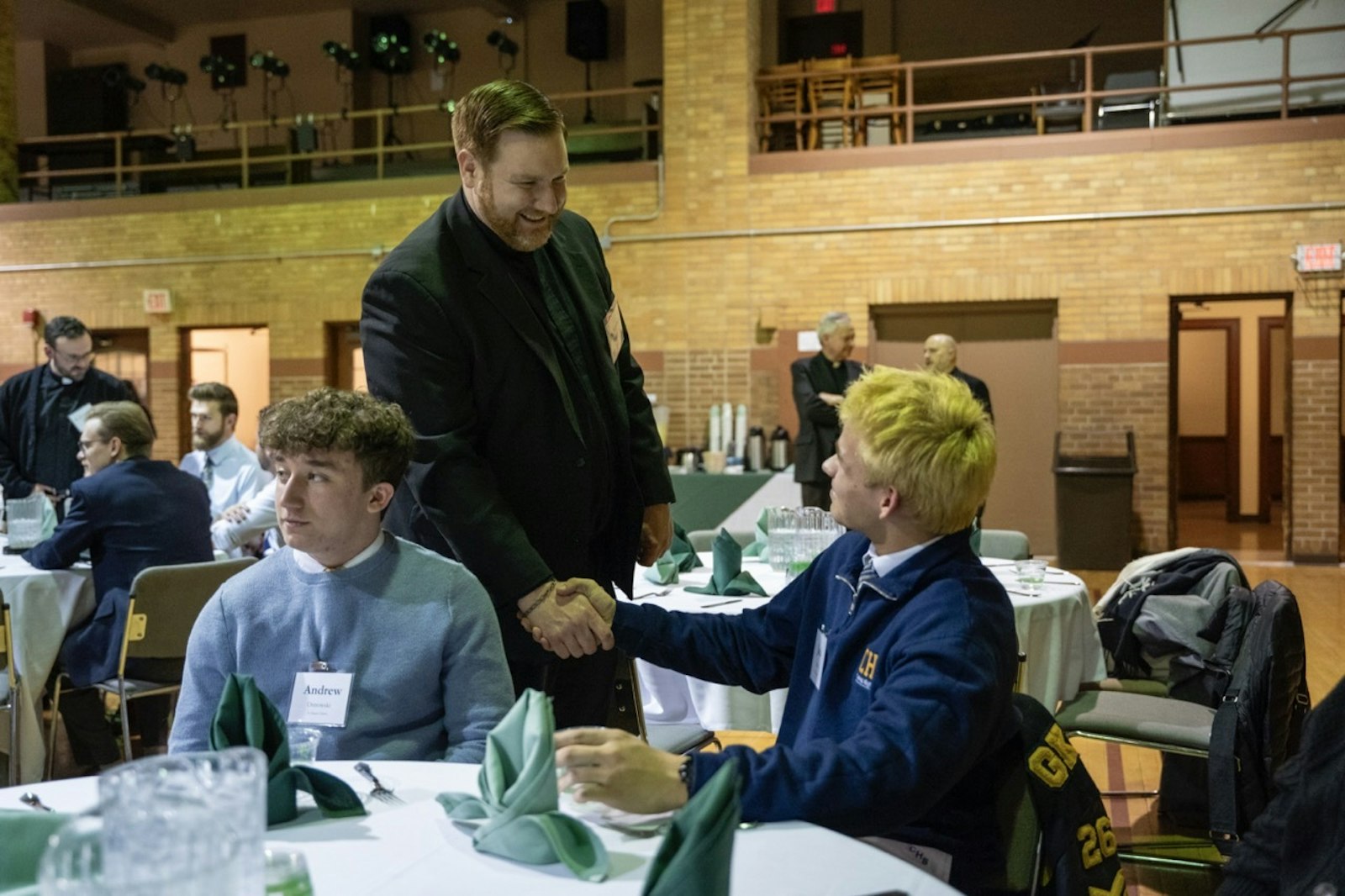 Fr. Stephen Pullis, graduate pastoral formation director at Sacred Heart Major Seminary, greets a high school student during the event. During dinner, the young men had an opportunity to ask the seminarians, priests and Archbishop Vigneron about their lives in the Church.