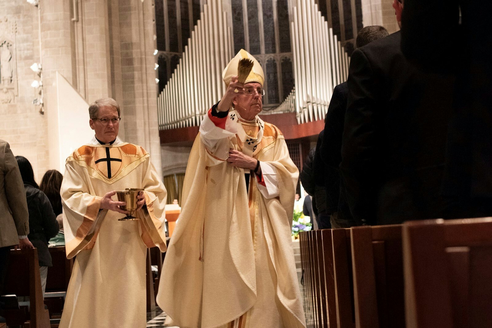 El arzobispo Vigneron rocía con agua bendita a los feligreses después de invitarlos a renovar sus promesas bautismales mientras el diácono Michael Van Dyke asiste durante la vigilia de Pascua en la Catedral del Santísimo Sacramento.