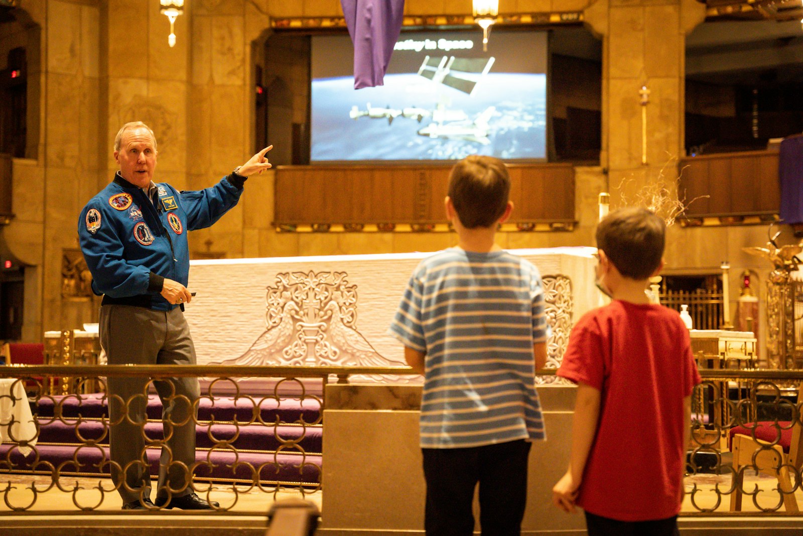 Jones explaining his role and mission aboard the International Space Station to two young boys the “Live at the Basilica” speaker series April 6. Jones was inspired as a boy watching the Apollo 16 mission.