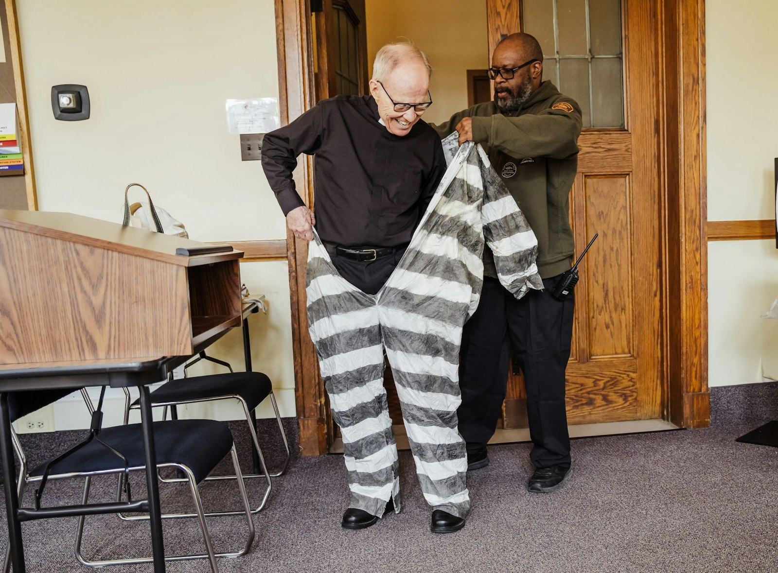 A security guard at Sacred Heart Major Seminary helps Fr. Cassidy don his "prisoner's clothing" for a photo shoot promoting Fr. Cassidy's latest book, "A Roman Commentary on St. Paul’s Letter to the Philippians," which details Paul's experience behind bars and the conditions under which he wrote his Letter to the Philippians.