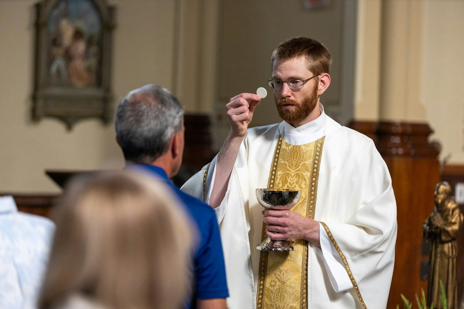 Fr. Caleb Cunningham, a newly ordained priest of the Diocese of Baker, Oregon, and a distant cousin of Blessed Solanus Casey, distributes Communion to the faithful during the feast day Mass, which was celebrated by Detroit Archbishop Allen H. Vigneron.