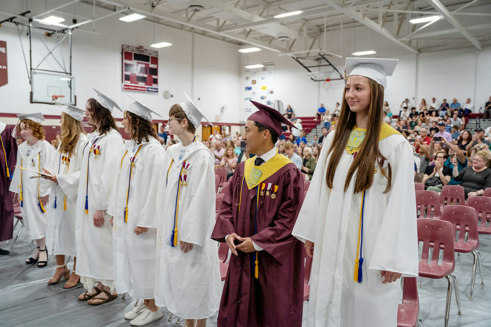 La generación 2024 se pone de pie mientras es reconocida por sus maestros de Gabriel Richard, padres, amigos y compañeros durante la ceremonia de graduación 2024 en el gimnasio de la escuela.