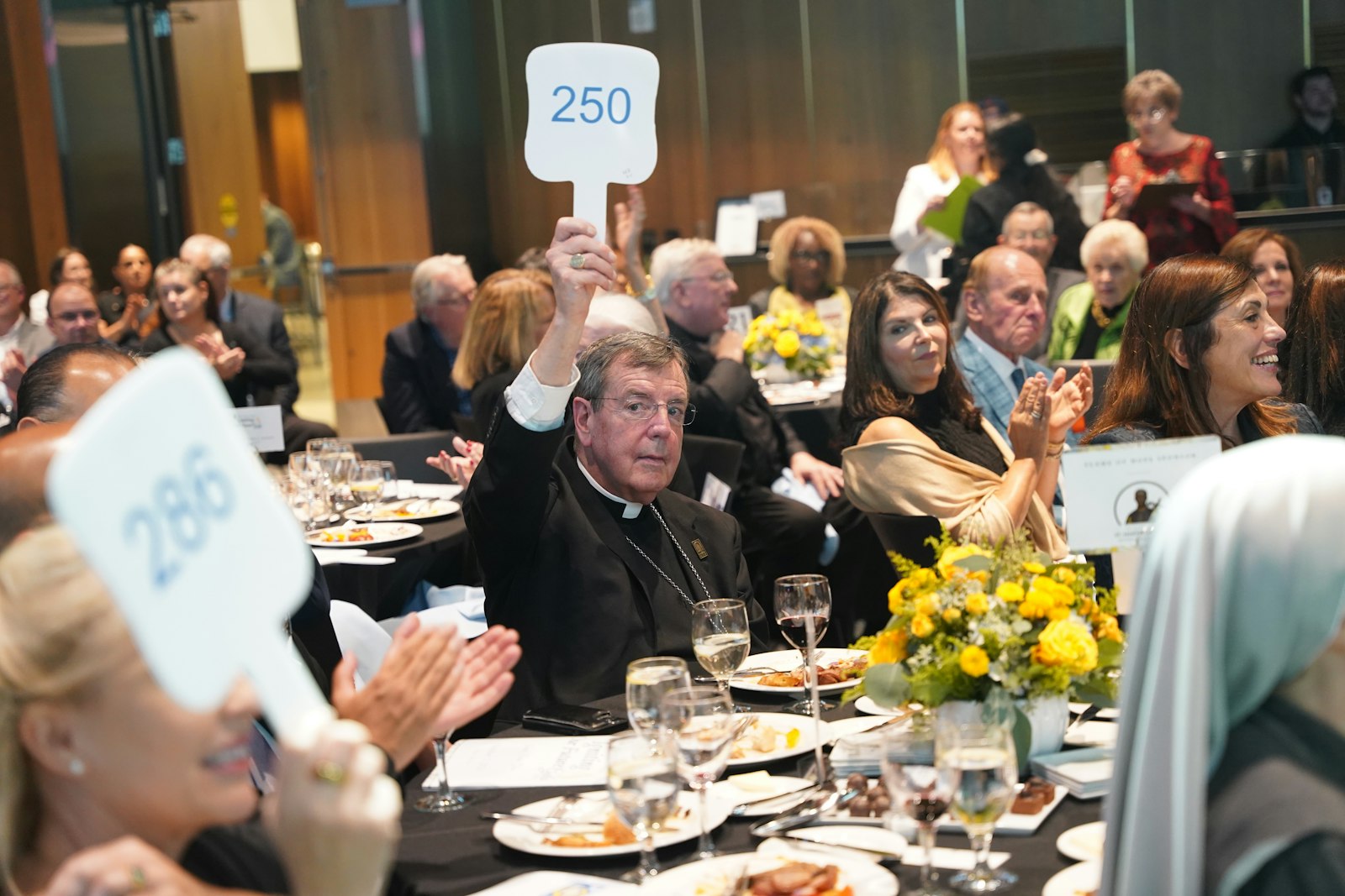 Detroit Archbishop Allen H. Vigneron raises his placard donate money to support scholarships for the children of Catholic school teachers.