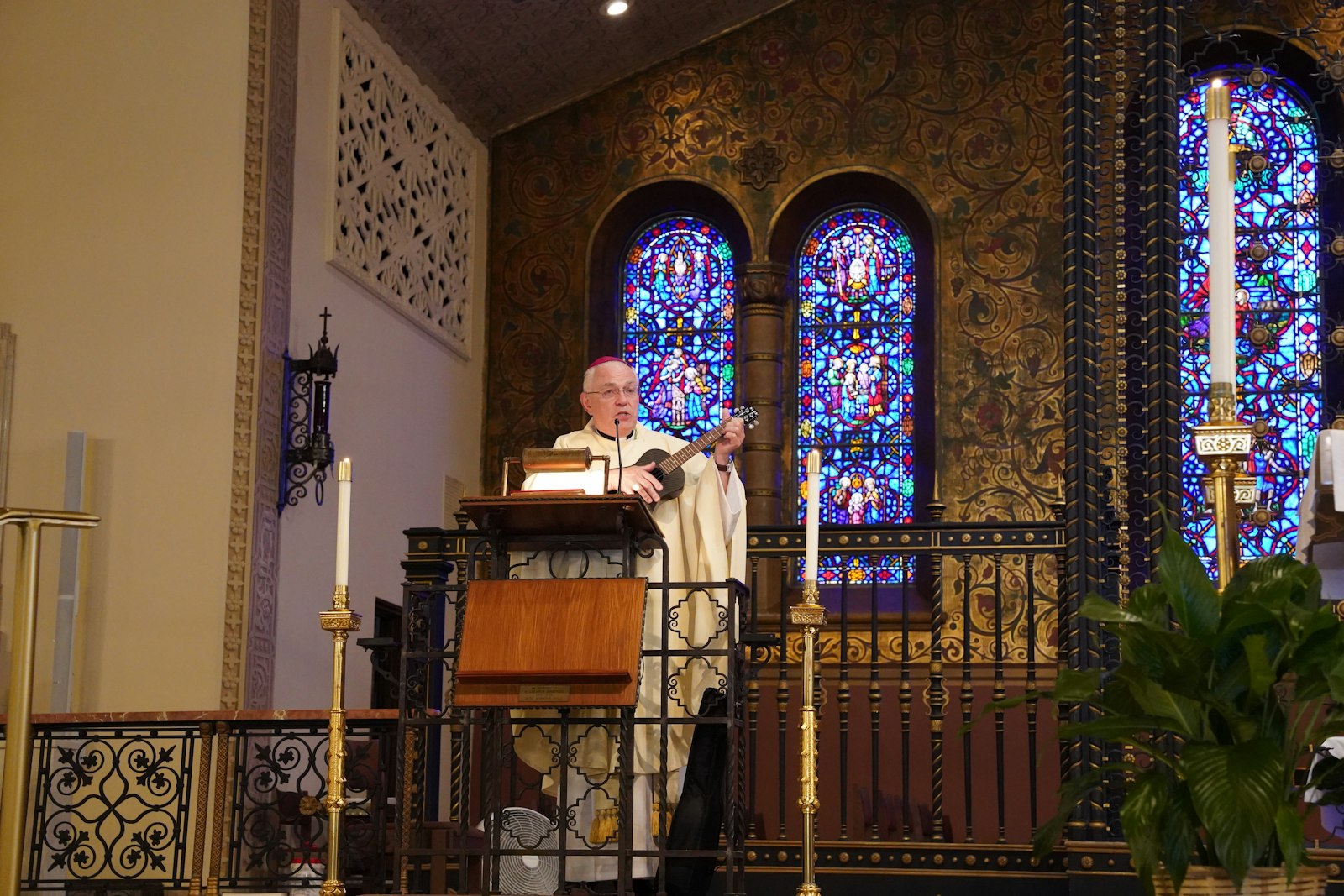 El obispo auxiliar de Detroit, Donald F. Hanchon, toca el ukelele durante su homilía en la misa de las 4 de la tarde para celebrar el centenario de Gesu.