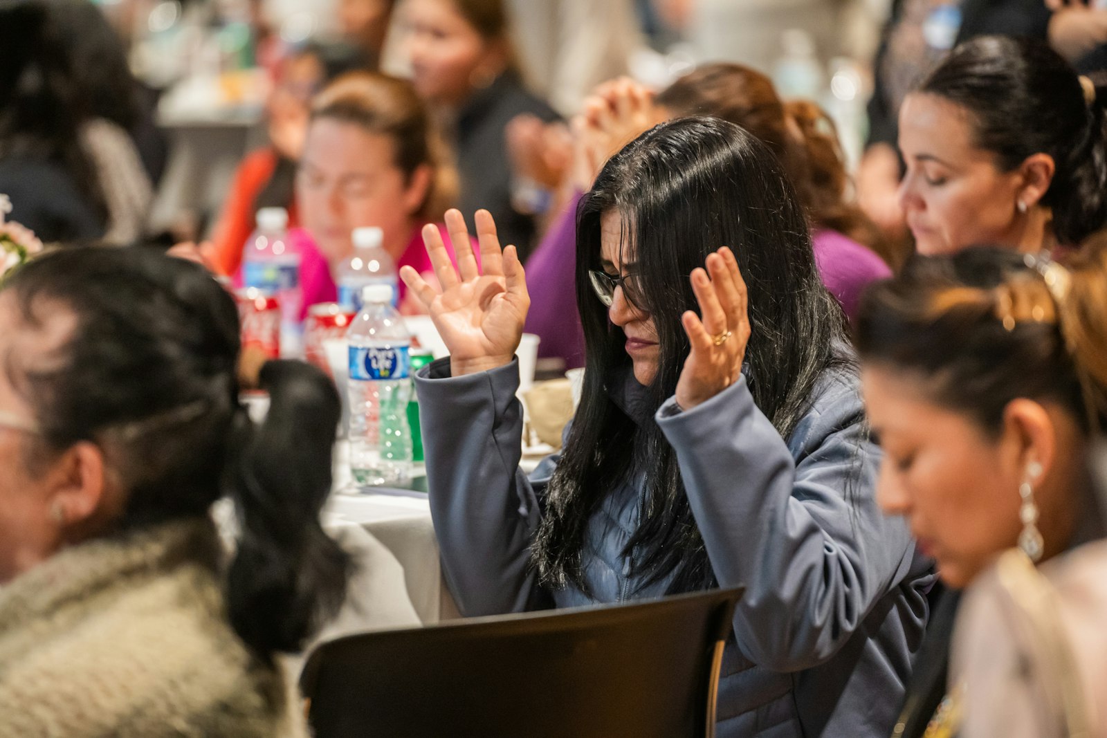 Women bow their heads in prayer during the 14th Hispanic Women's Conference on Oct. 29, 2023, at the Dearborn Performing Arts Center. (Valaurian Waller | Detroit Catholic)