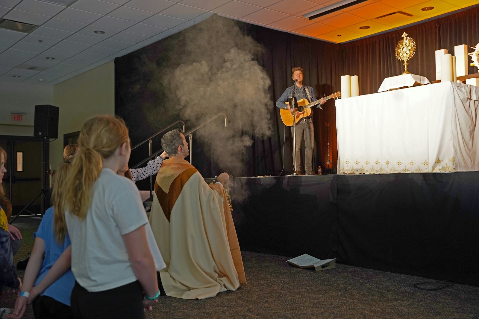 Fr. Mario Amore of St. Aloysius Parish in Detroit leads Eucharistic adoration at the Holy Fire Great Lakes conference while Anderson performs praise-and-worship music on his guitar.