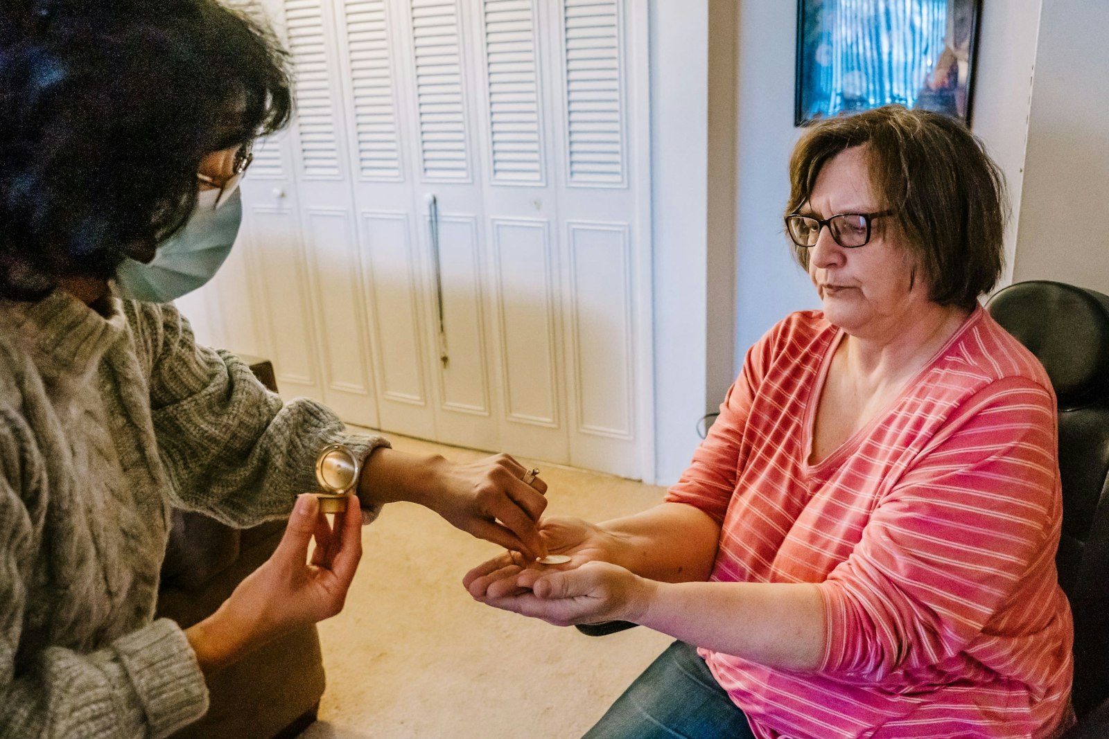 Marlene Gouba receives the Eucharist from May Faraon, a volunteer from the Church of the Holy Family, on Jan. 14.