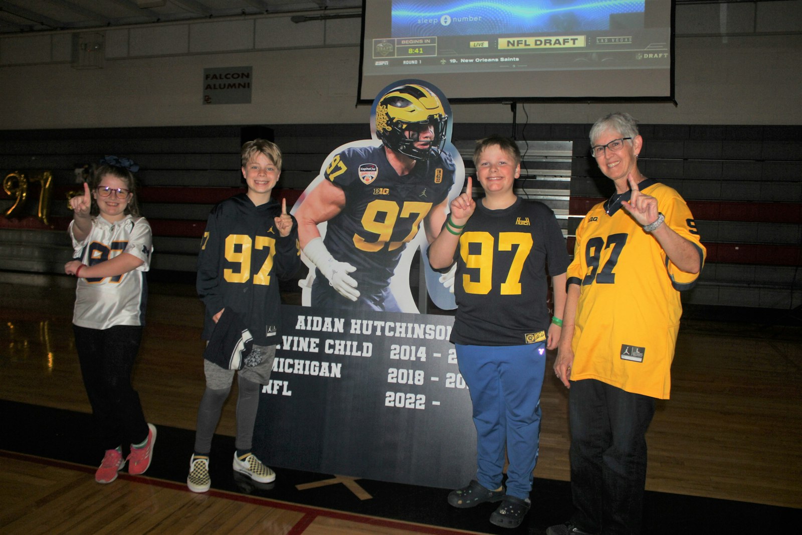 Superfans Monroe Mark of Divine Child, Sam Grezlik and Griffin Gardner from Our Lady of Good Counsel, and Divine Child science teacher Patti Poirer gather around a cardboard standee of Aidan Hutchinson during the NFL Draft Party held at Divine Child High School in Dearborn on April 28. (Wright Wilson | Special to Detroit Catholic)