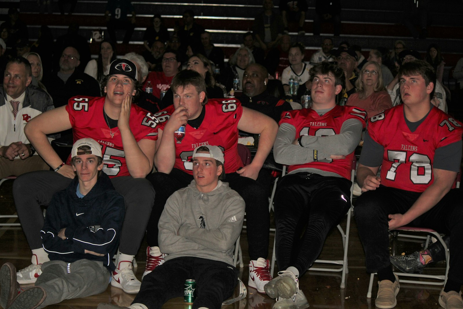 Divine Child football players watch the big screen, anticipating the announcement of the National Football League’s top draft selection.