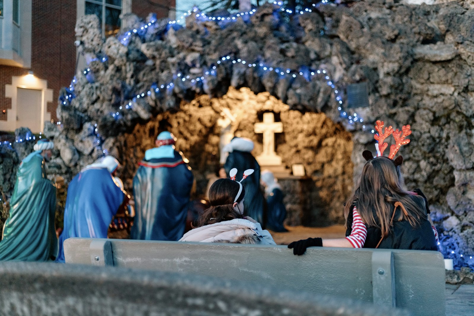 Two girls pray before a life-sized Nativity on display at the campus' Marian grotto. (Alissa Tuttle | Special to Detroit Catholic)
