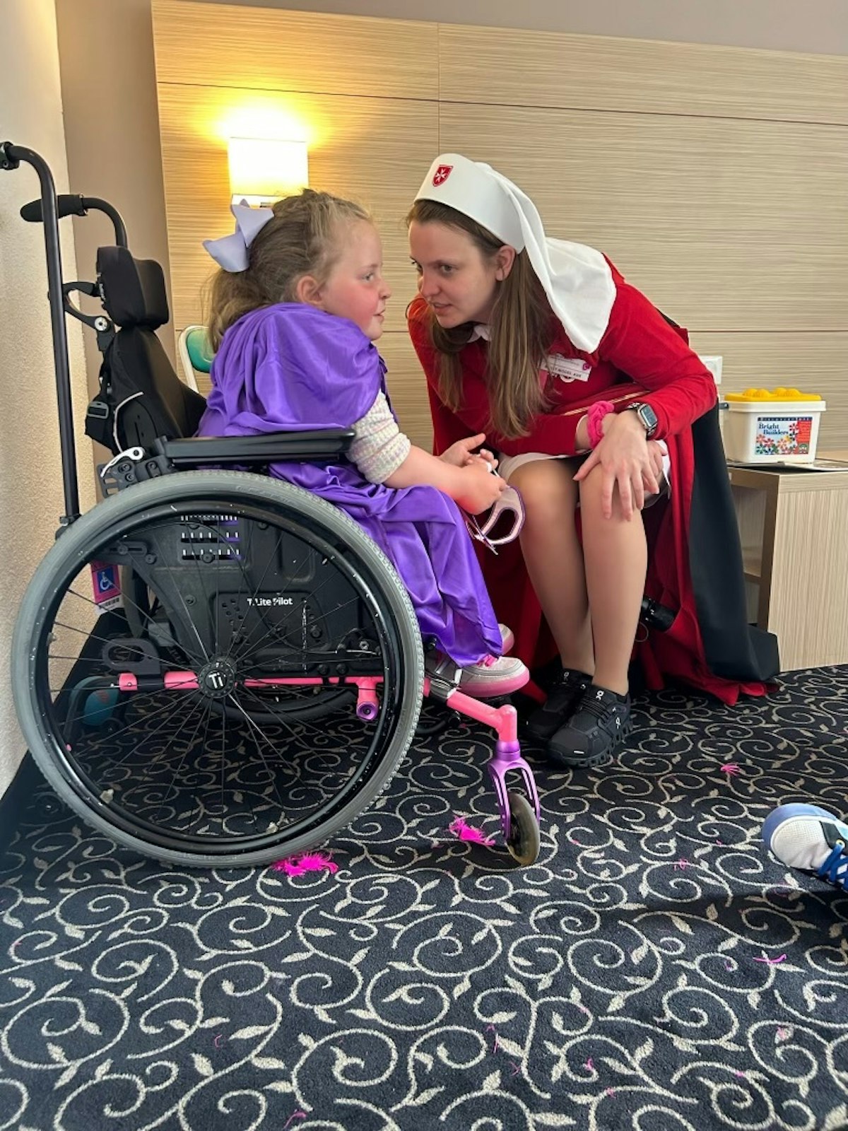 Modes cares for one of the "malades" accompanying the Order of Malta on this year's pilgrimage.  As an adult, she decided to pursue nursing and today helps other children afflicted with illnesses like hers.