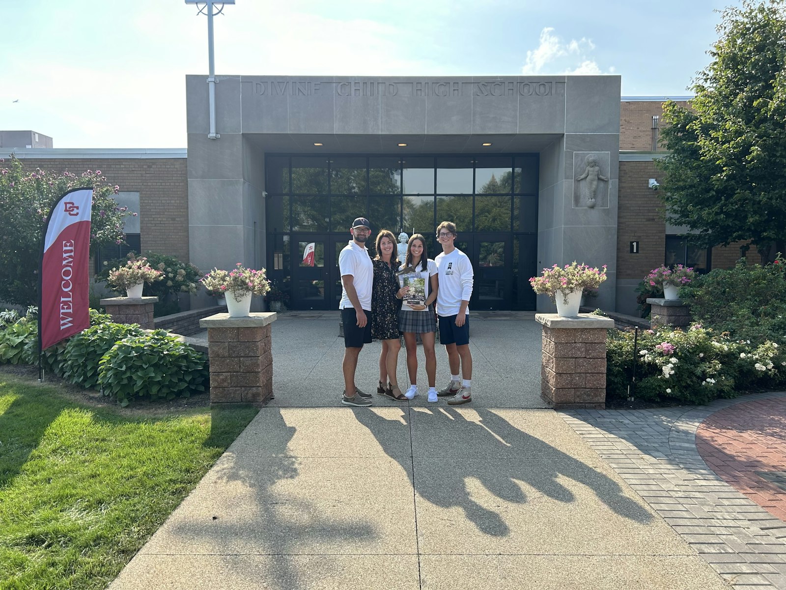 Evan and Beppie Murray stand in front of Divine Child High School in Dearborn with their daughter, Cecilia, and son, Charlie. Cecilia, a senior at Divine Child, is holding brochures from colleges to which she plans to apply. Her brother, Charlie, is a freshman at Eastern Michigan University. (Courtesy photo)