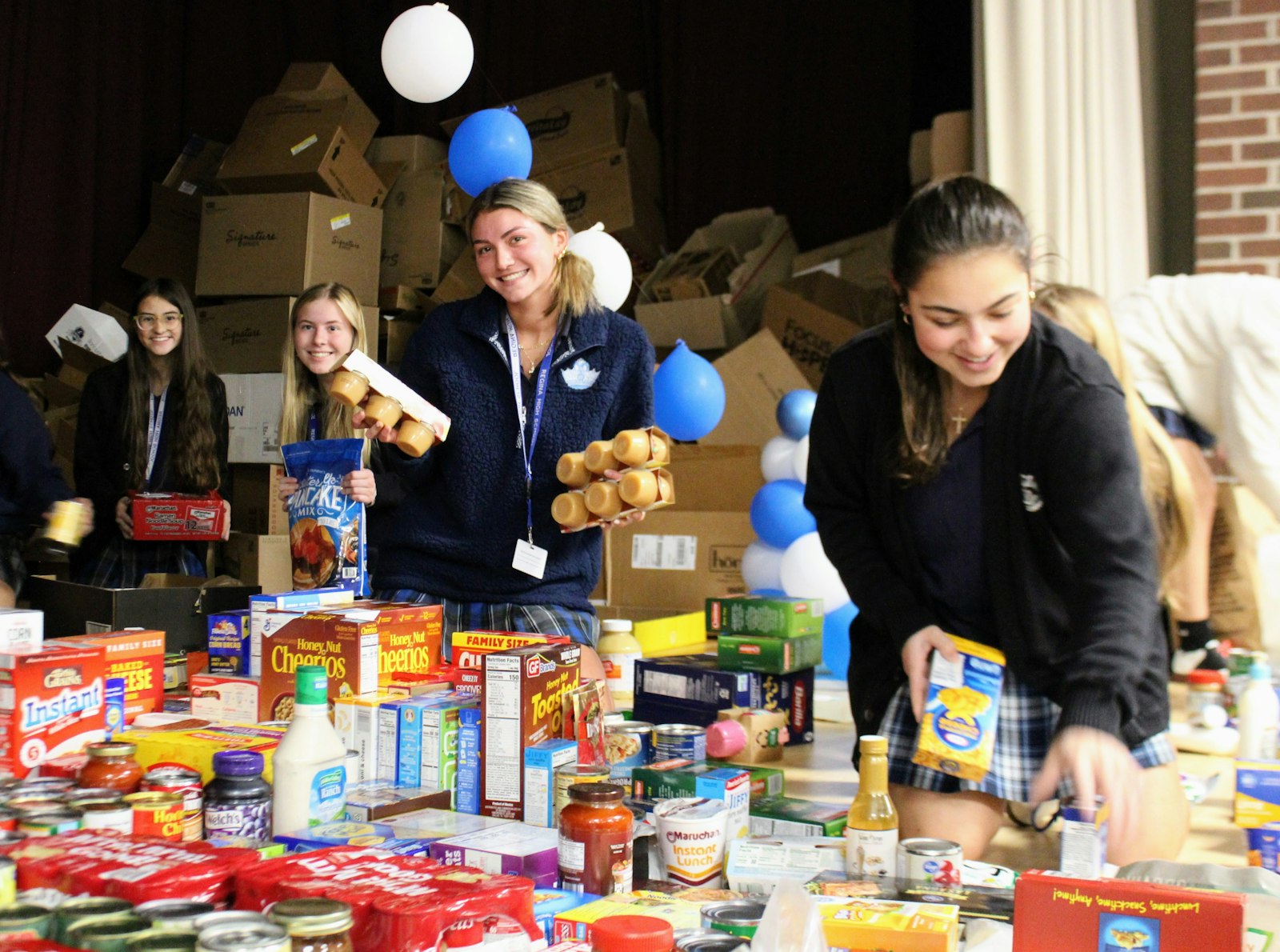 Regina High School students packed the entire stage in the cafeteria with nonperishable good, fulfilling its goal for its food drive and earning an extra day off for their Thanksgiving break. The donated items are going to six food pantries in the Detroit area. (Photo courtesy of Regina High School)