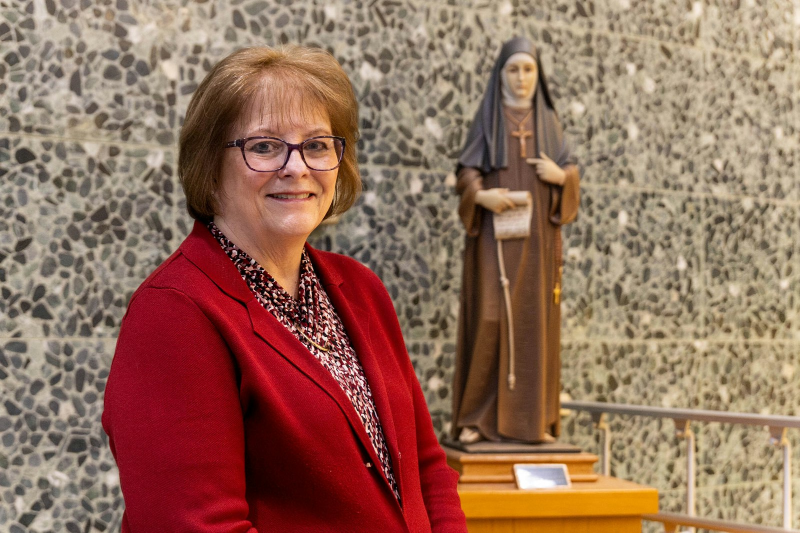 Burnett, a parishioner at St. Kateri Tekakwitha Parish in Dearborn, said she carries the Franciscan values of service to those in need in her pastoral care. She is pictured with a statue of St. Clare of Assisi at Madonna University in Livonia.