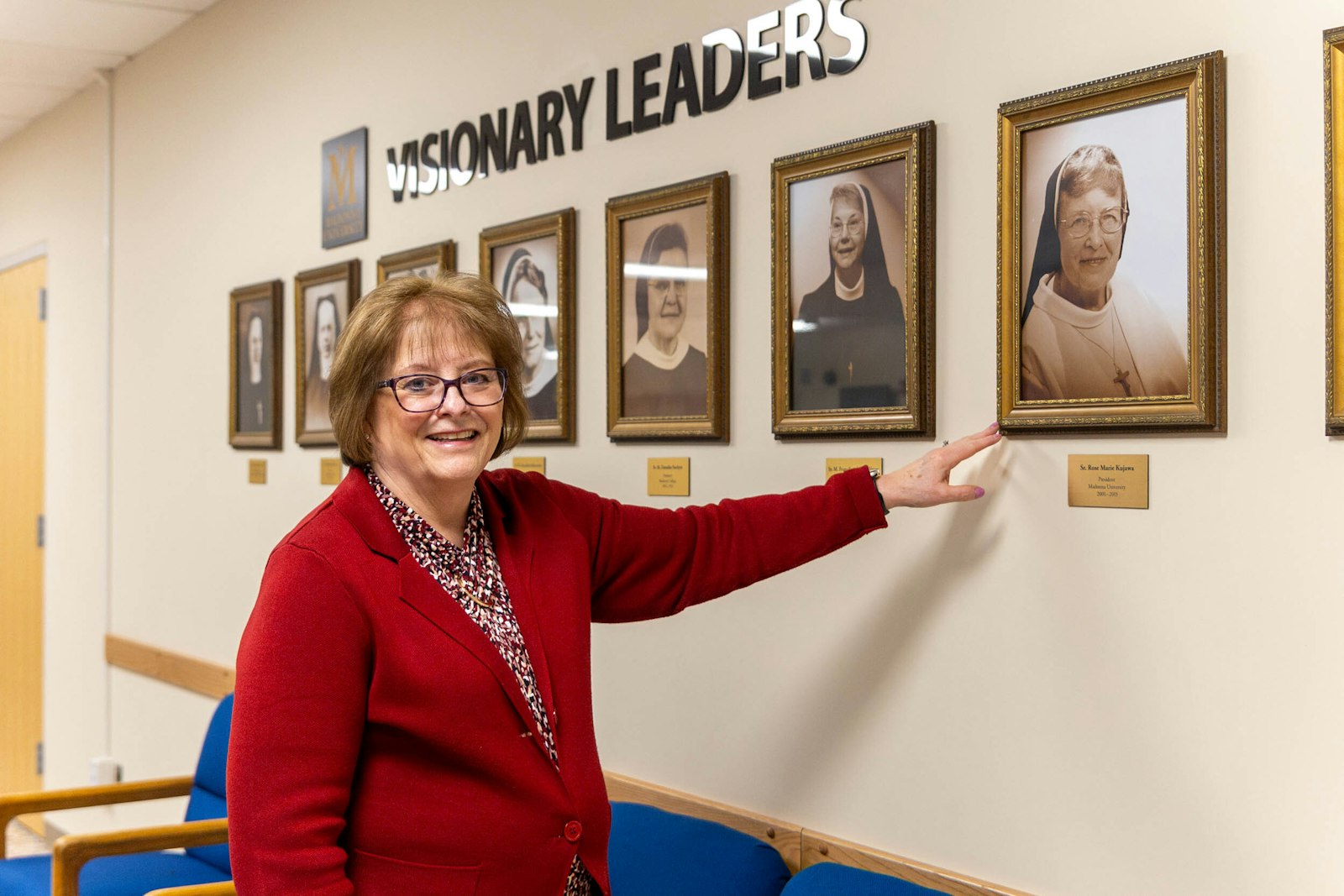 Marianne Burnett points out a portrait of Sr. Rose Marie Kujawa, CSSF, who led Madonna University as its president from 2001-15, in the spirit of the school's Franciscan tradition.