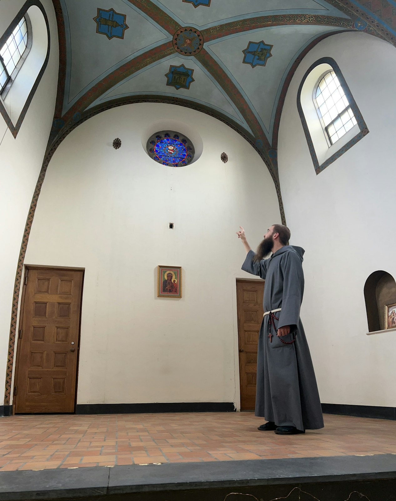 A friar points out a stained-glass window above where the altar will be placed inside the chapel, which is currently undergoing renovations. The chapel's name will have a Marian theme, Fr. Fornwalt said.