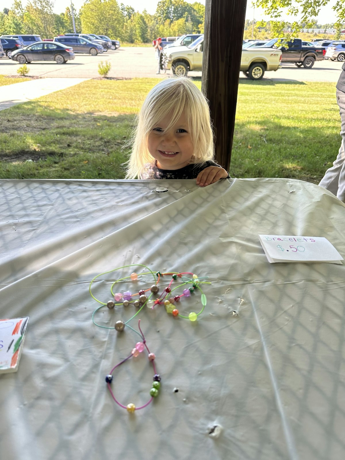 One of two 3-year-olds to sell her handmade creations at the Junior Makers Market, Bernadette stands beside a table ready to sell the bracelets she made. All four of her bracelets were sold.