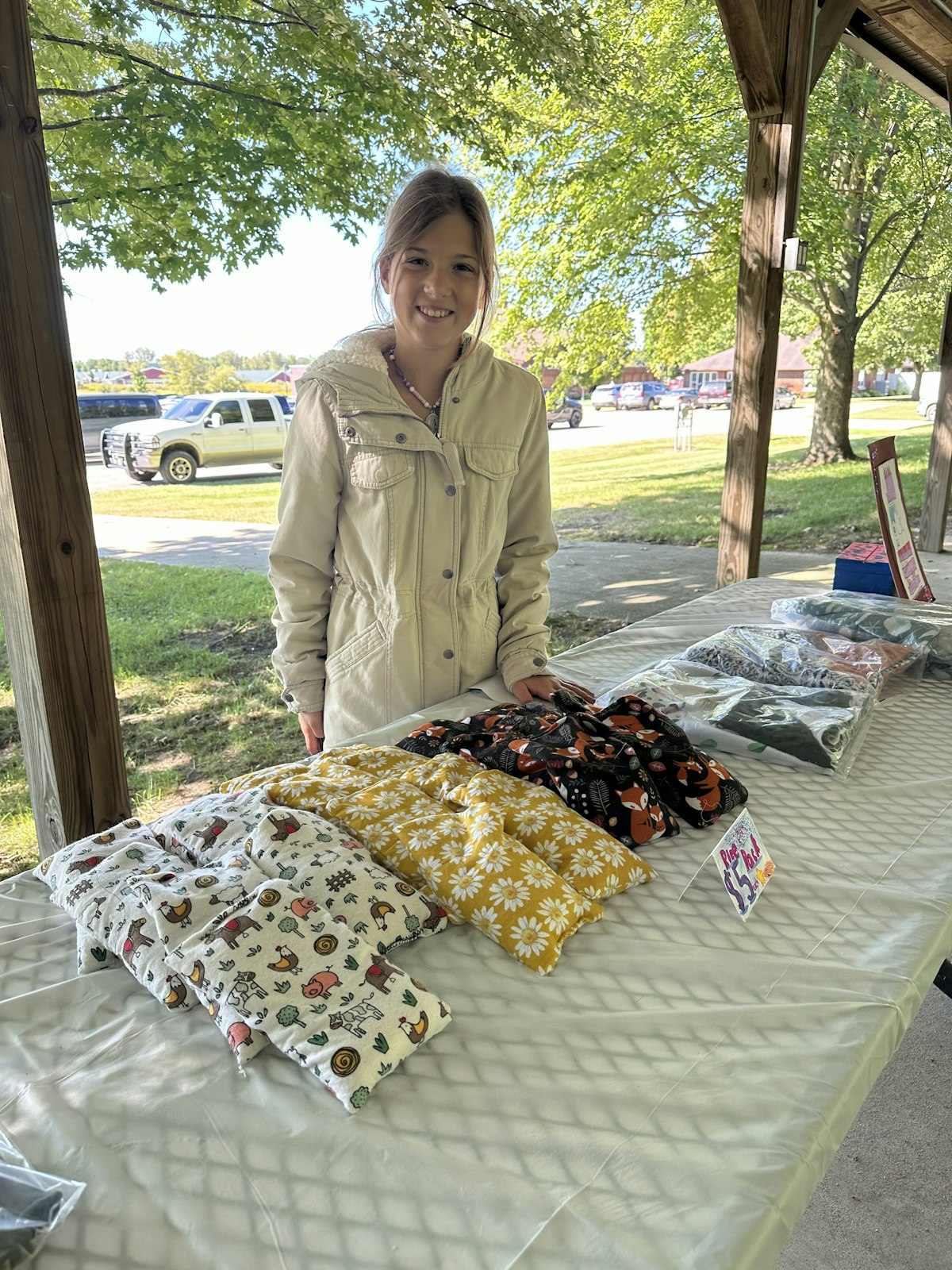 A 12-year-old stands ready to sell the blankets she sewed. She sold out of her inventory and then took orders from enthusiastic customers.