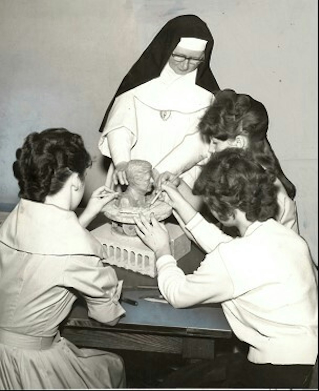 Girls at Vista Maria gather around a statue of President John F. Kennedy. Date unknown.